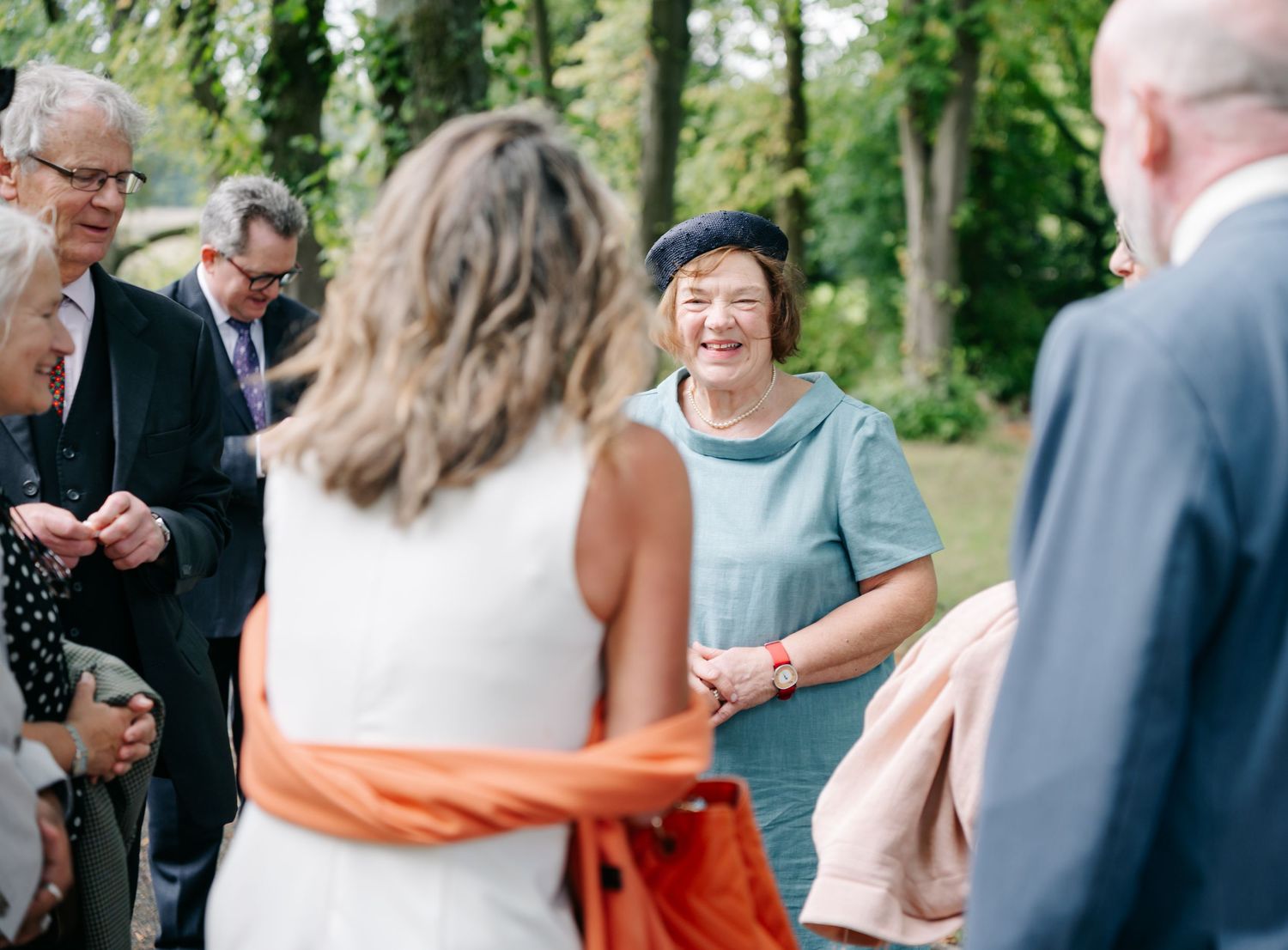 A group of wedding guests gathered outdoors sharing joyful conversation during a celebration.