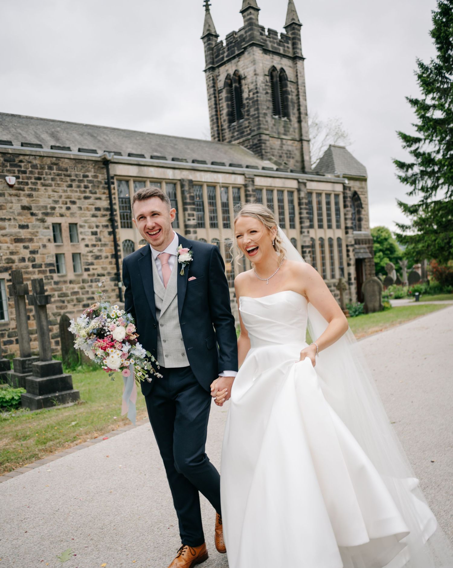 A happy couple shares joyful moments together outside a grand stone church building on their wedding day.