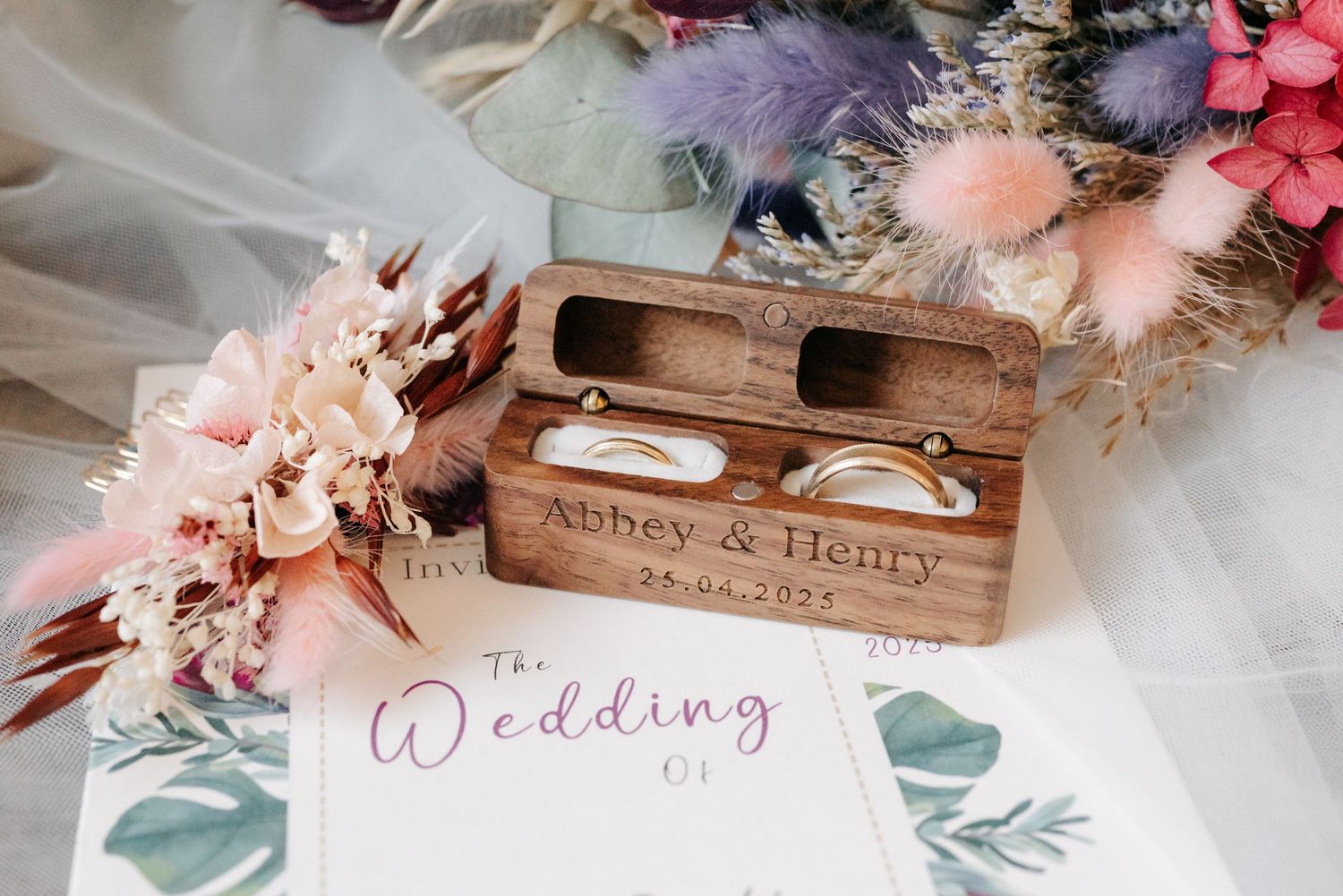 Rustic wedding details with pink flowers, wooden signs, and delicate tulle decor arranged on a vintage table.