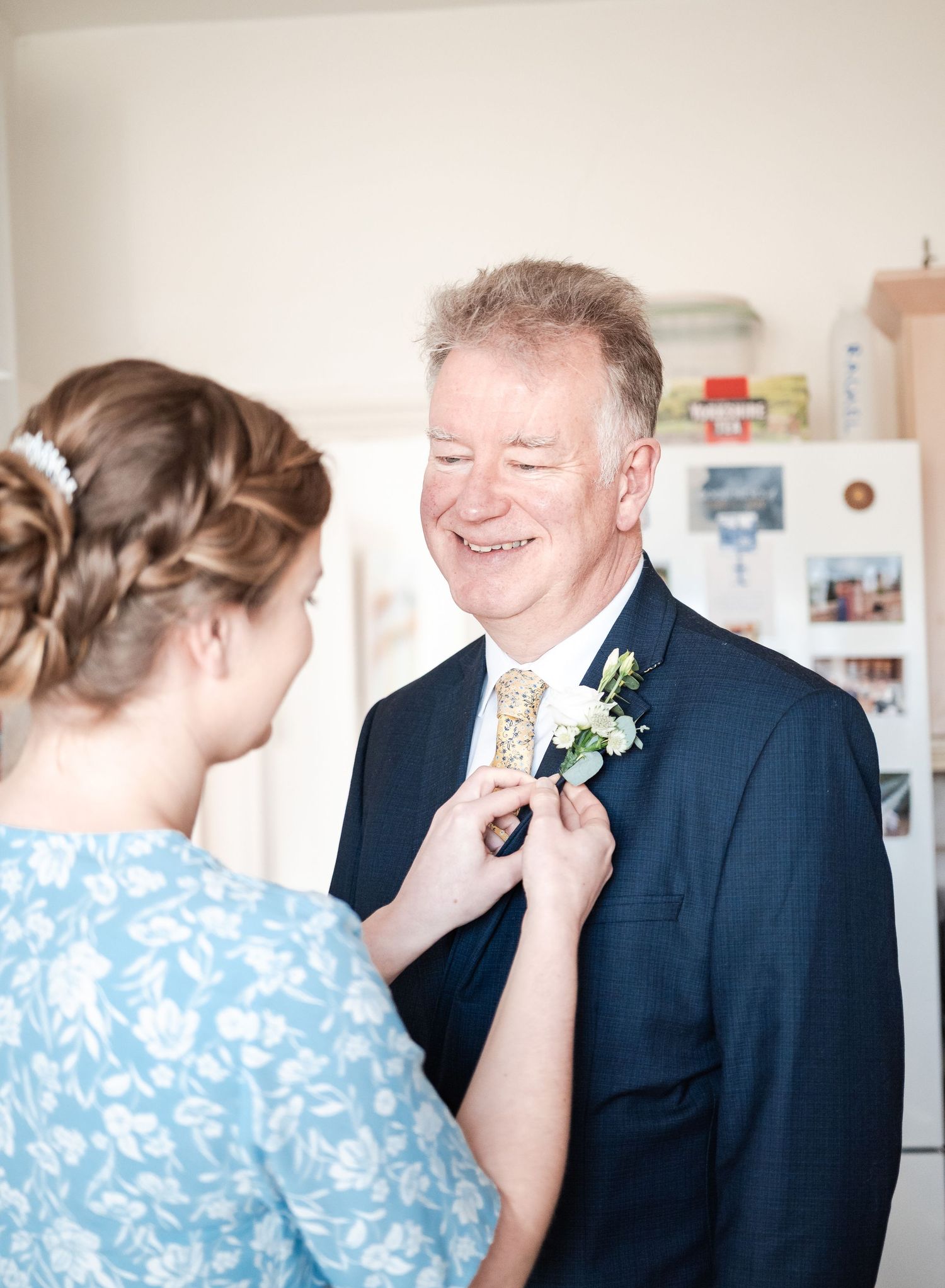 A couple shares a tender moment during a wedding first look, with one wearing a light blue dress and another in a dark suit.