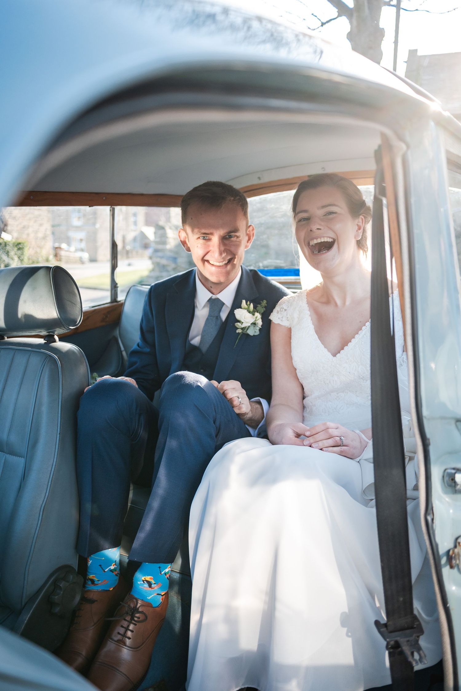 Candid wedding moments shared inside classic car with white leather seats.