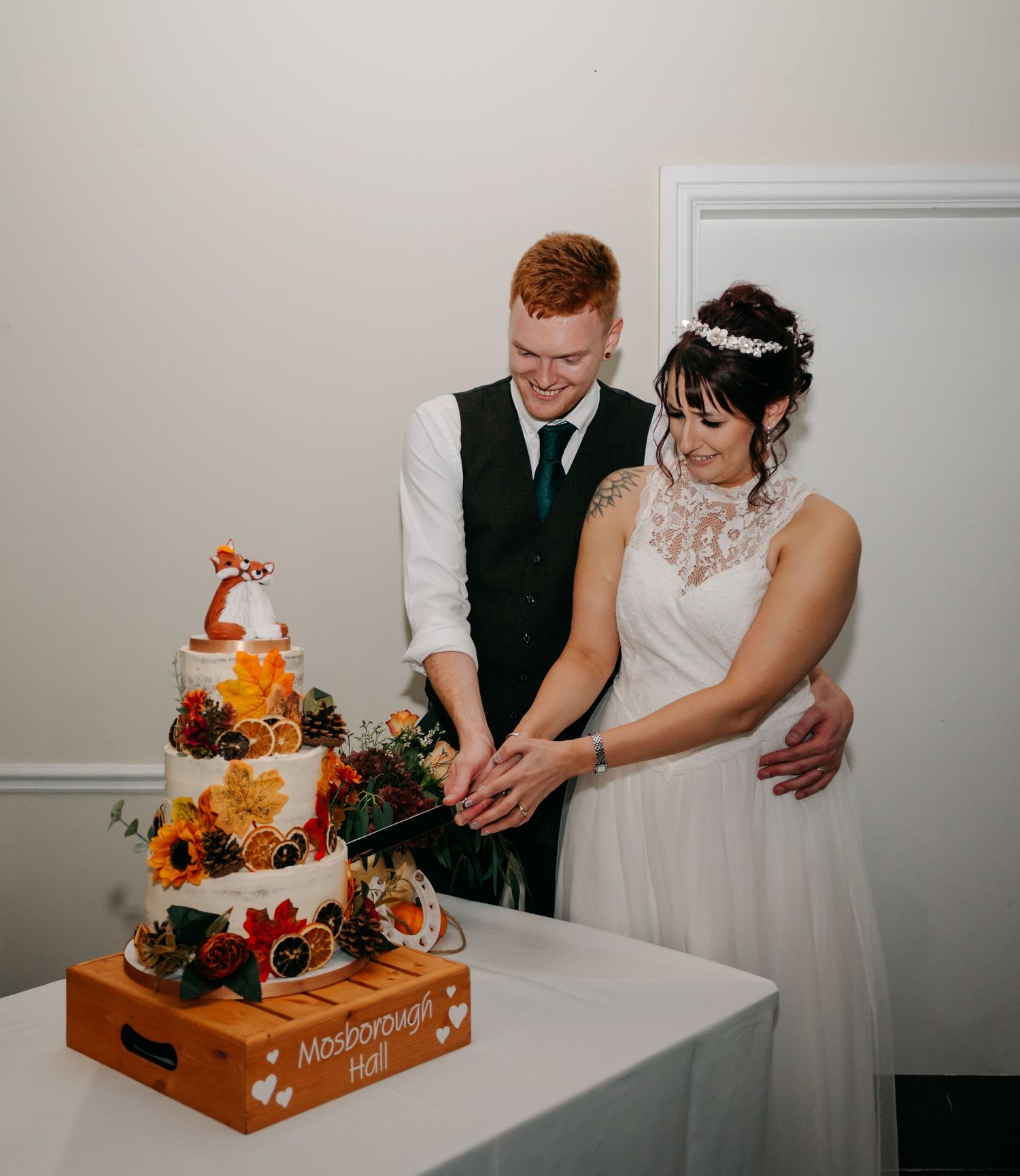Newlyweds cutting their autumn-themed wedding cake together.
