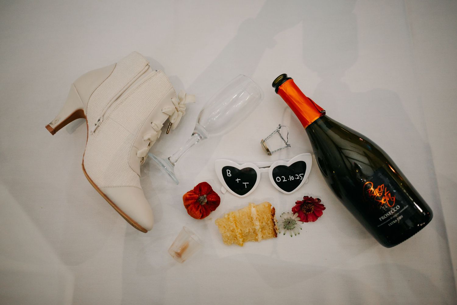 Wedding reception table details with wine bottles and scattered rose petals.