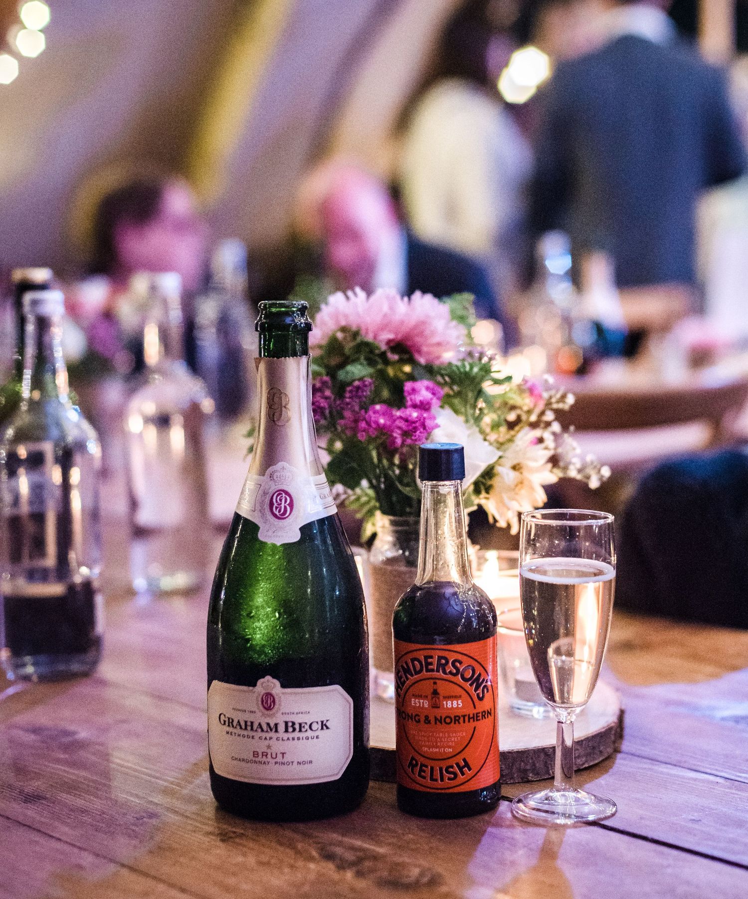 Champagne bottles and floral centerpieces on rustic wooden table at wedding reception.