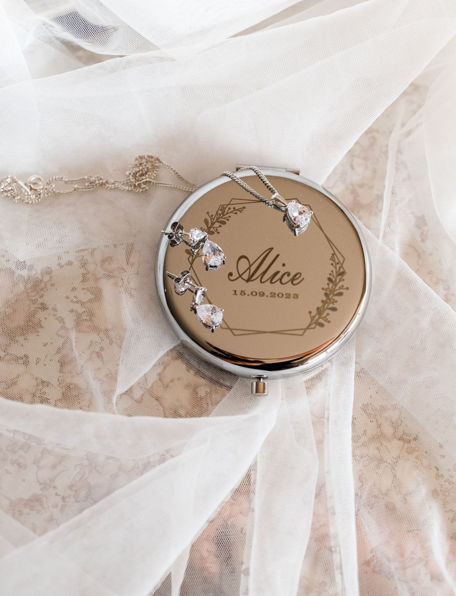 Delicate compact mirror with floral design on white tulle fabric.
