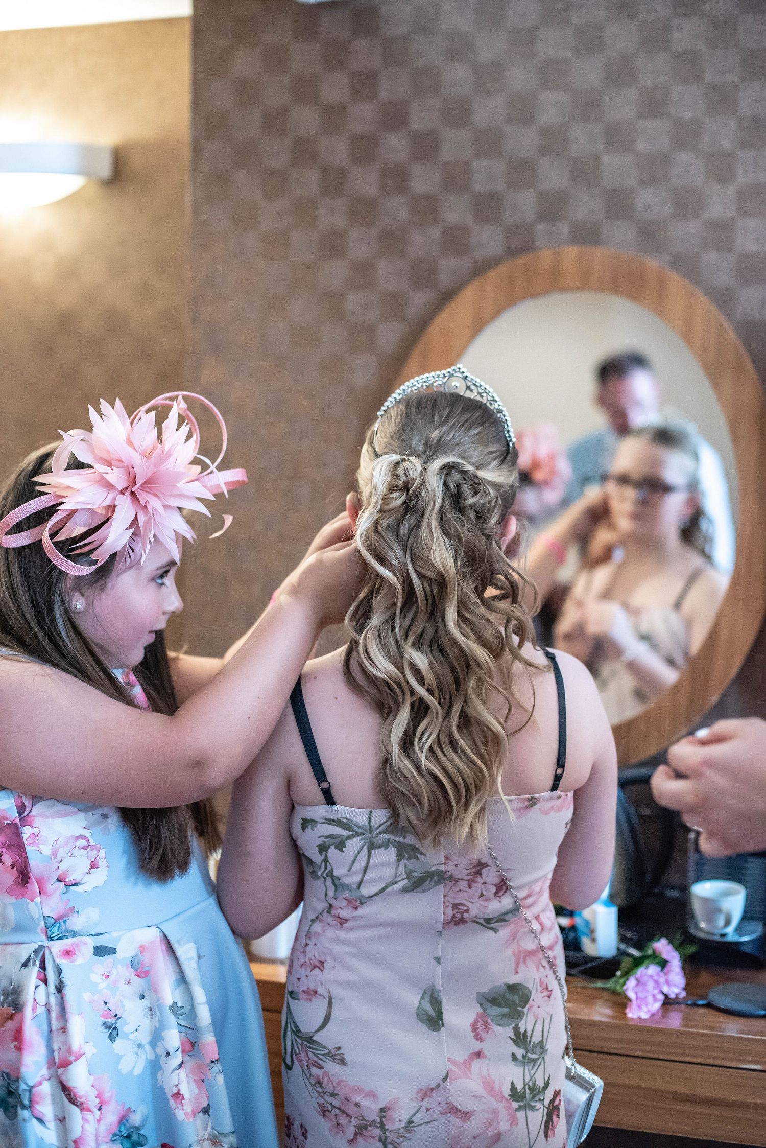 Wedding preparation scene showing hairstyling with pink floral accessories.