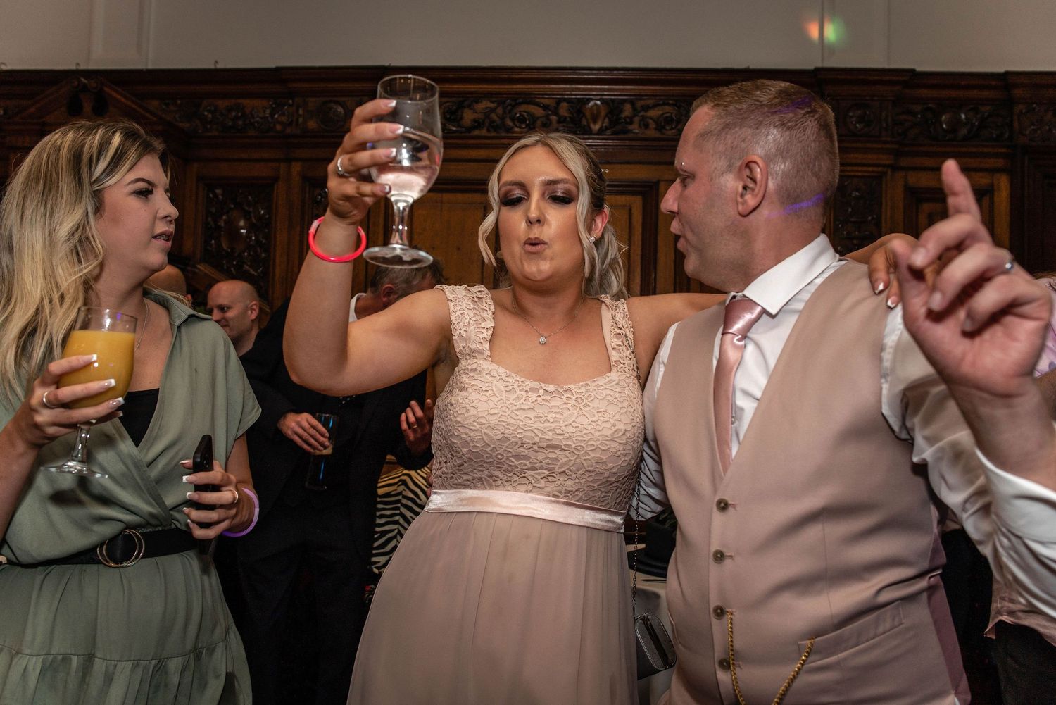 Wedding party raising their glasses in a toast during reception celebrations.