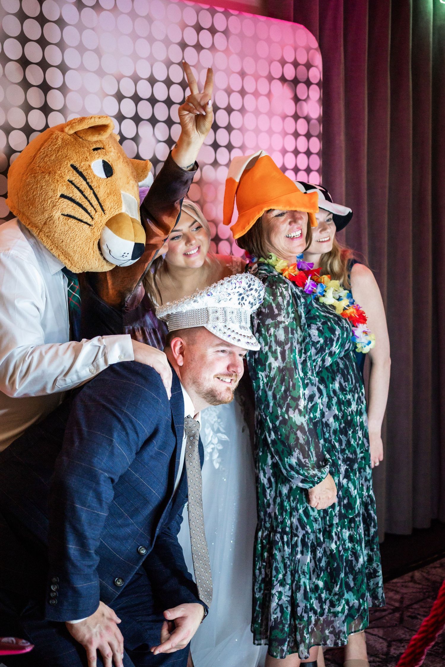 Wedding photo booth scene with fun costumes and a large mascot character.