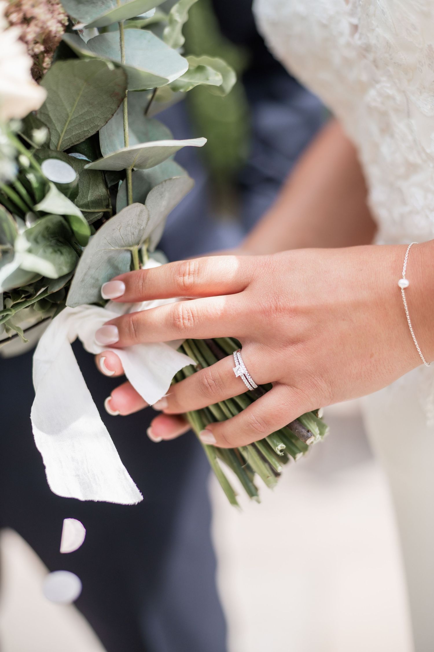 Close up of bridal bouquet with eucalyptus and wedding ring on hand.