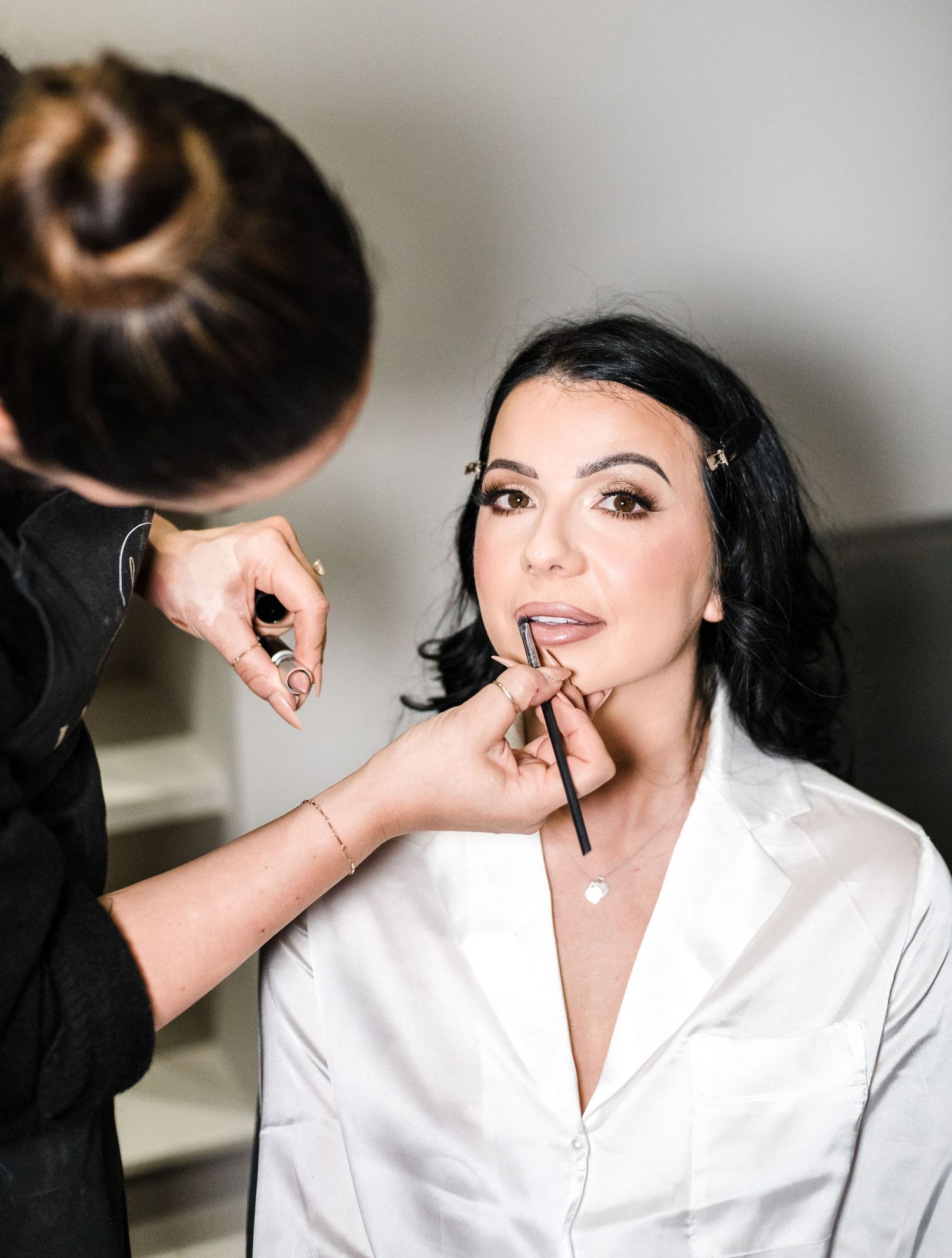 Makeup artist applying lipstick during bridal preparation.