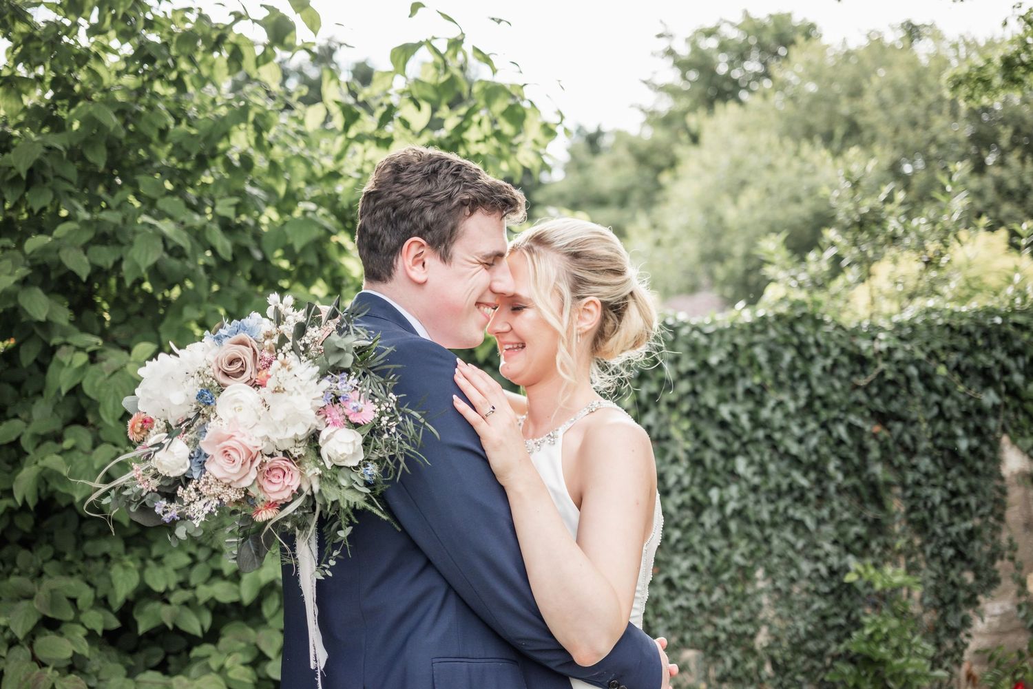 Romantic outdoor portrait of couple with pink and white floral bouquet.
