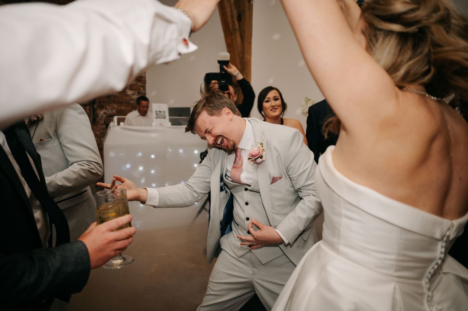 Wedding reception dance floor moments with guests celebrating in warm ambient lighting.
