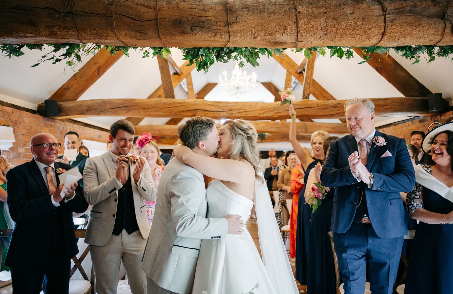 Wedding attendees gather in a rustic wooden barn venue during ceremony celebrations.