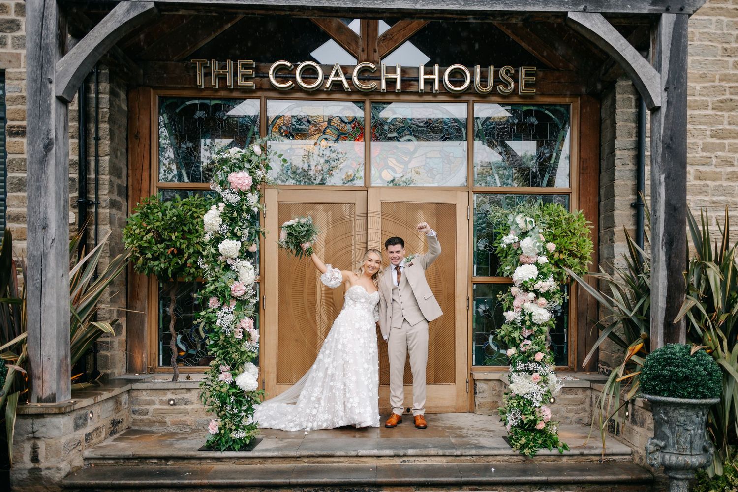 Wedding venue entrance decorated with floral arrangements and wooden beams at The Coach House.