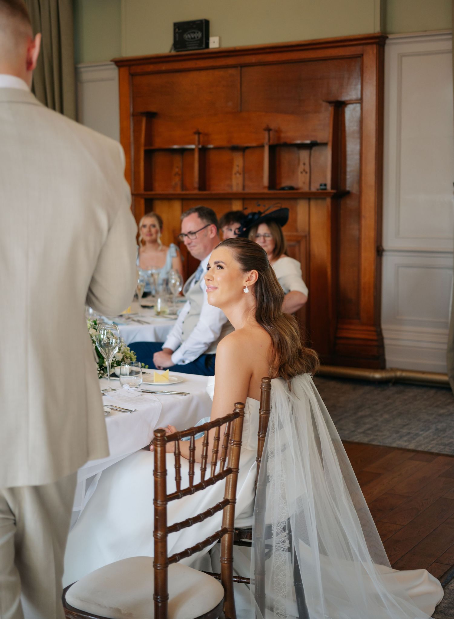 Wedding reception scene with wooden chairs and elegant table settings in a traditional venue.