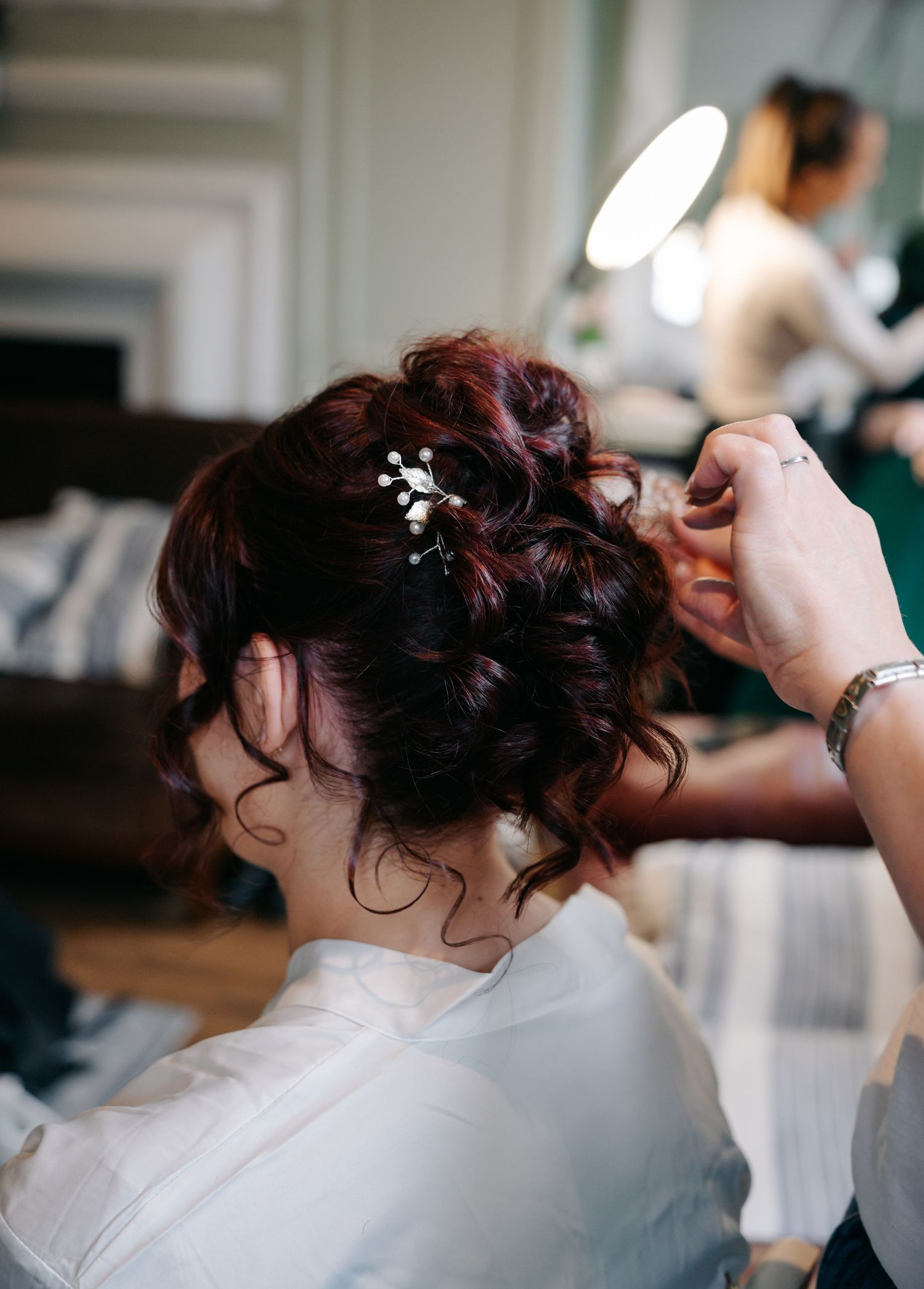 Hair stylist arranging an elegant updo hairstyle with decorative pins.