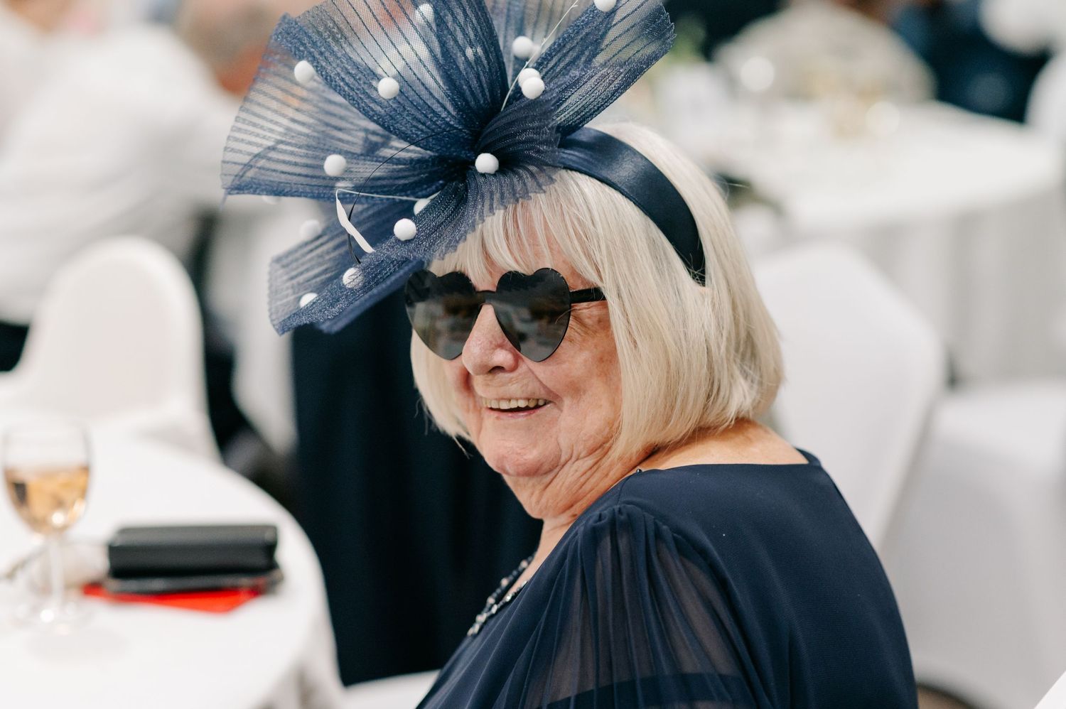 Wedding guests wearing elegant blue fascinators at an outdoor ceremony.