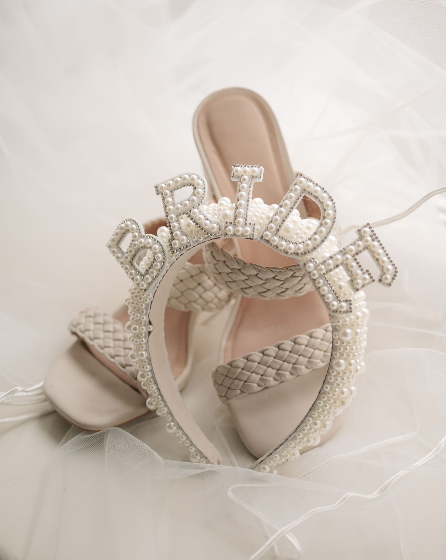 Elegant bridal headpiece with pearl and crystal embellishments displayed on white tulle background.