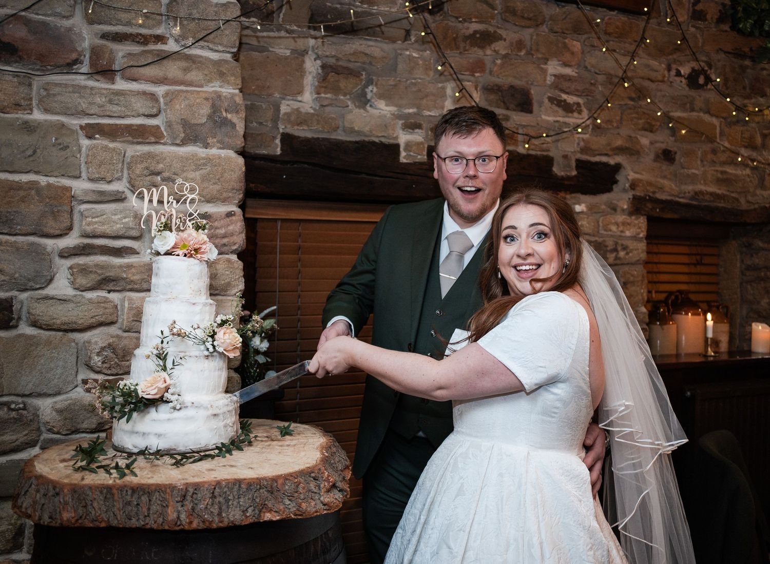 Wedding cake display against rustic stone wall at reception venue.