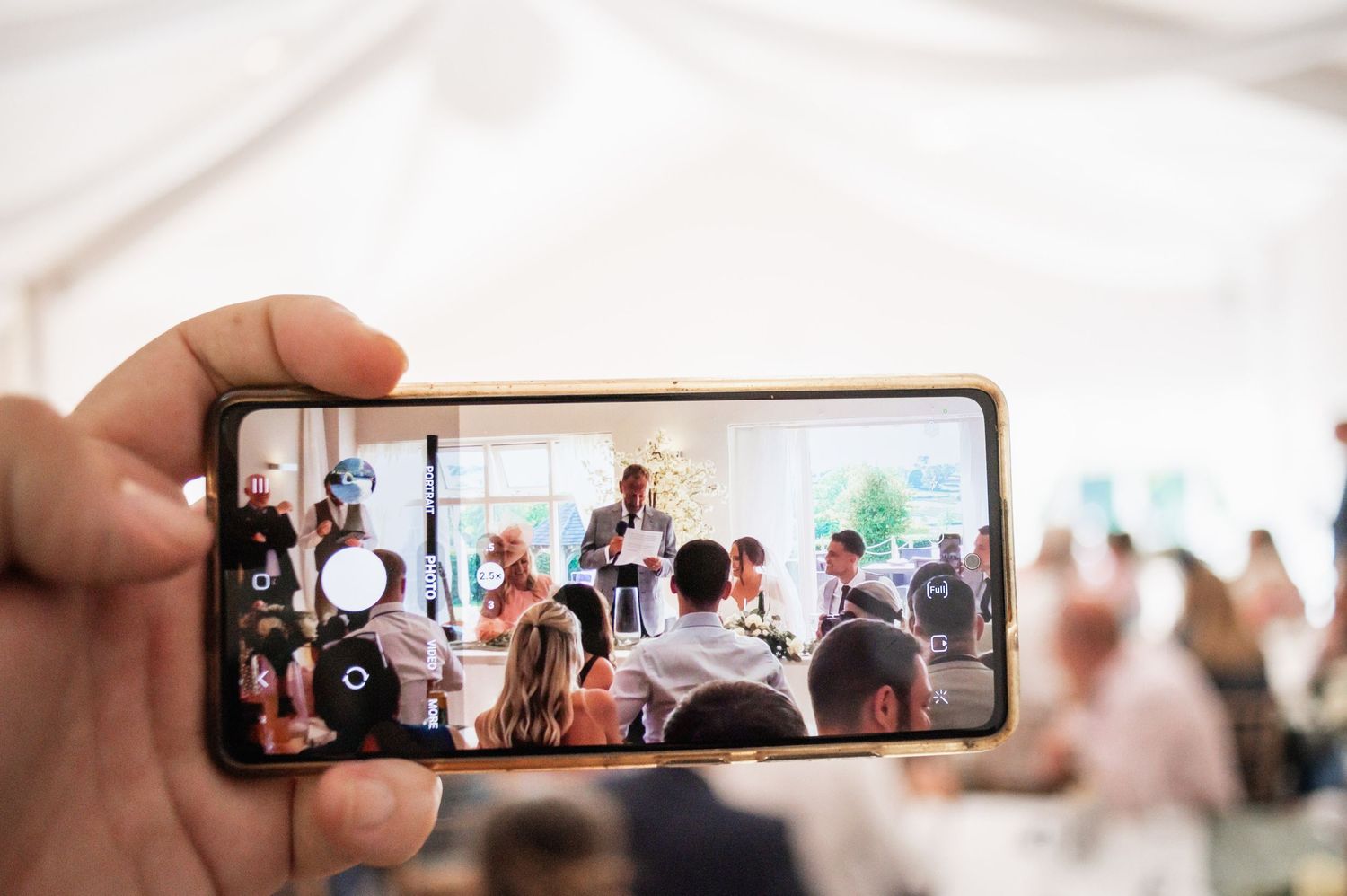 Hand holding smartphone capturing wedding celebration moment through device camera.