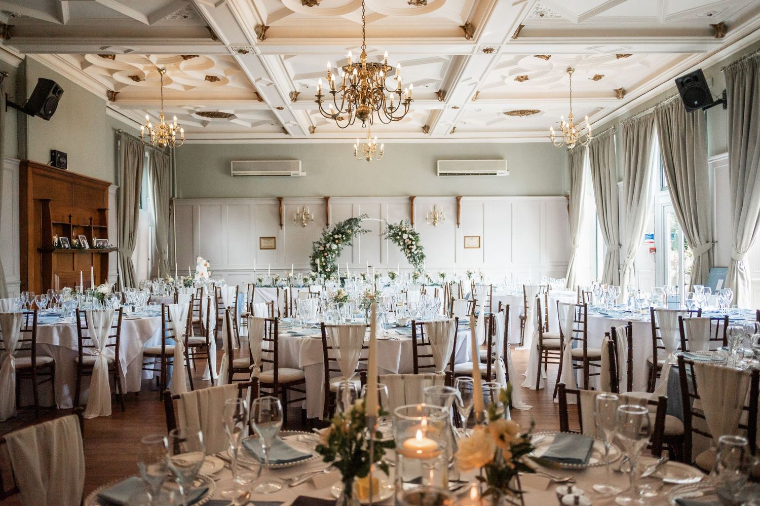 Elegant wedding reception room with chandelier and white table settings.