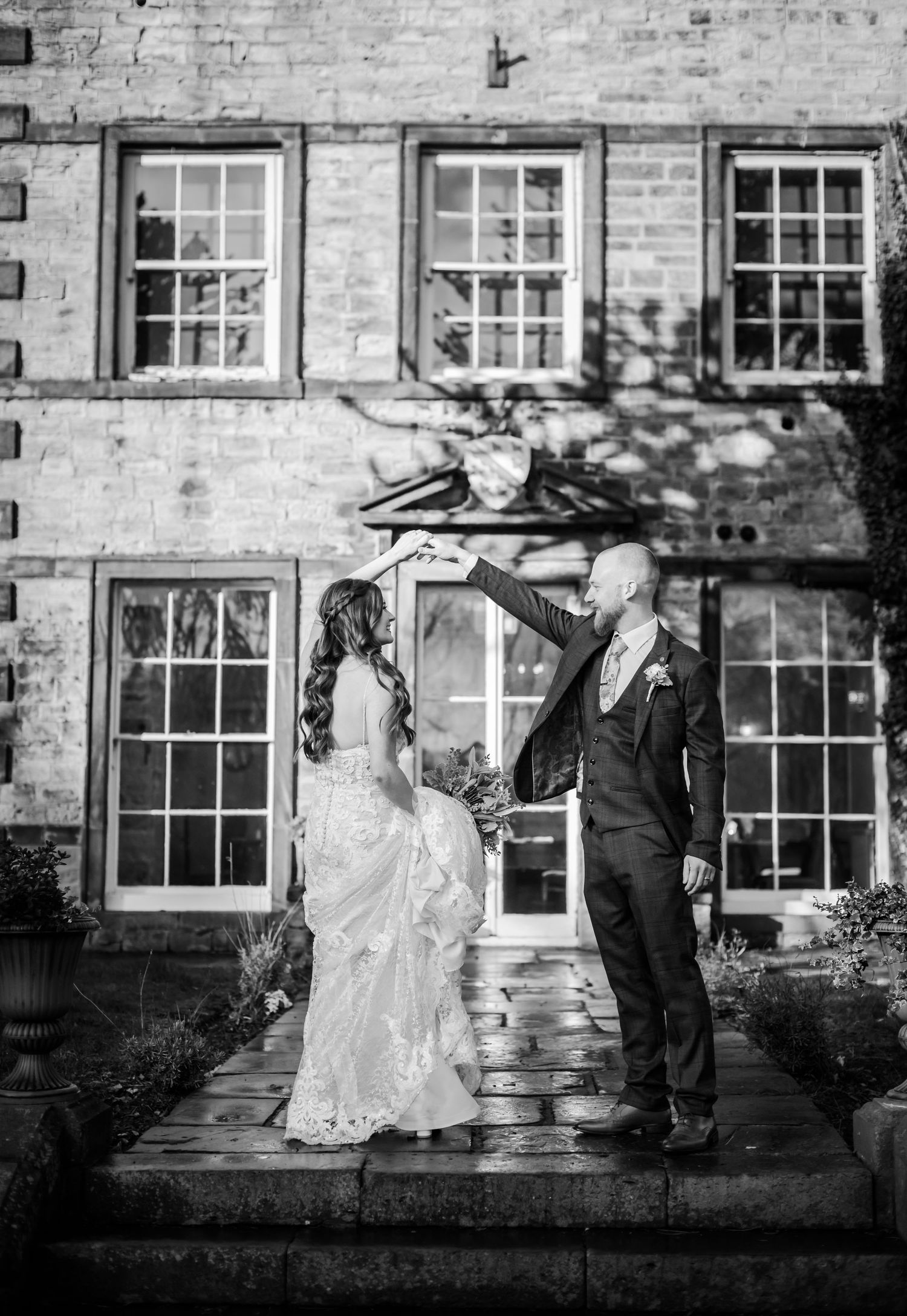 Black and white wedding portrait in front of historic stone building with elegant window details.