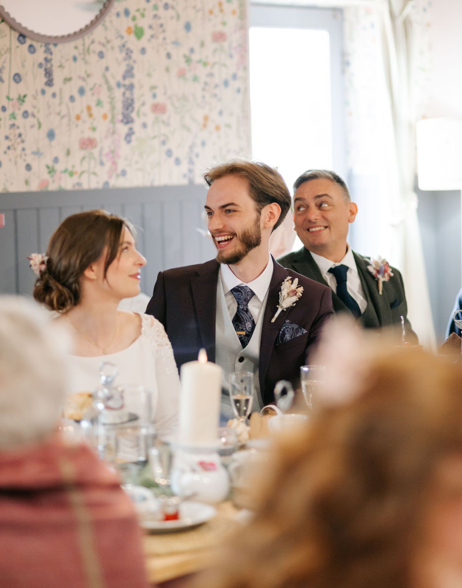 Wedding reception guests share joyful moments at a decorated table during an intimate celebration.