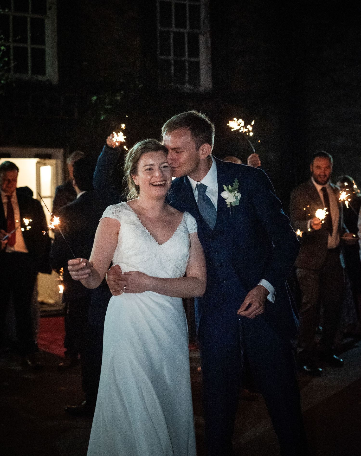 Couple dances together during their wedding reception in a dimly lit venue with sparklers.