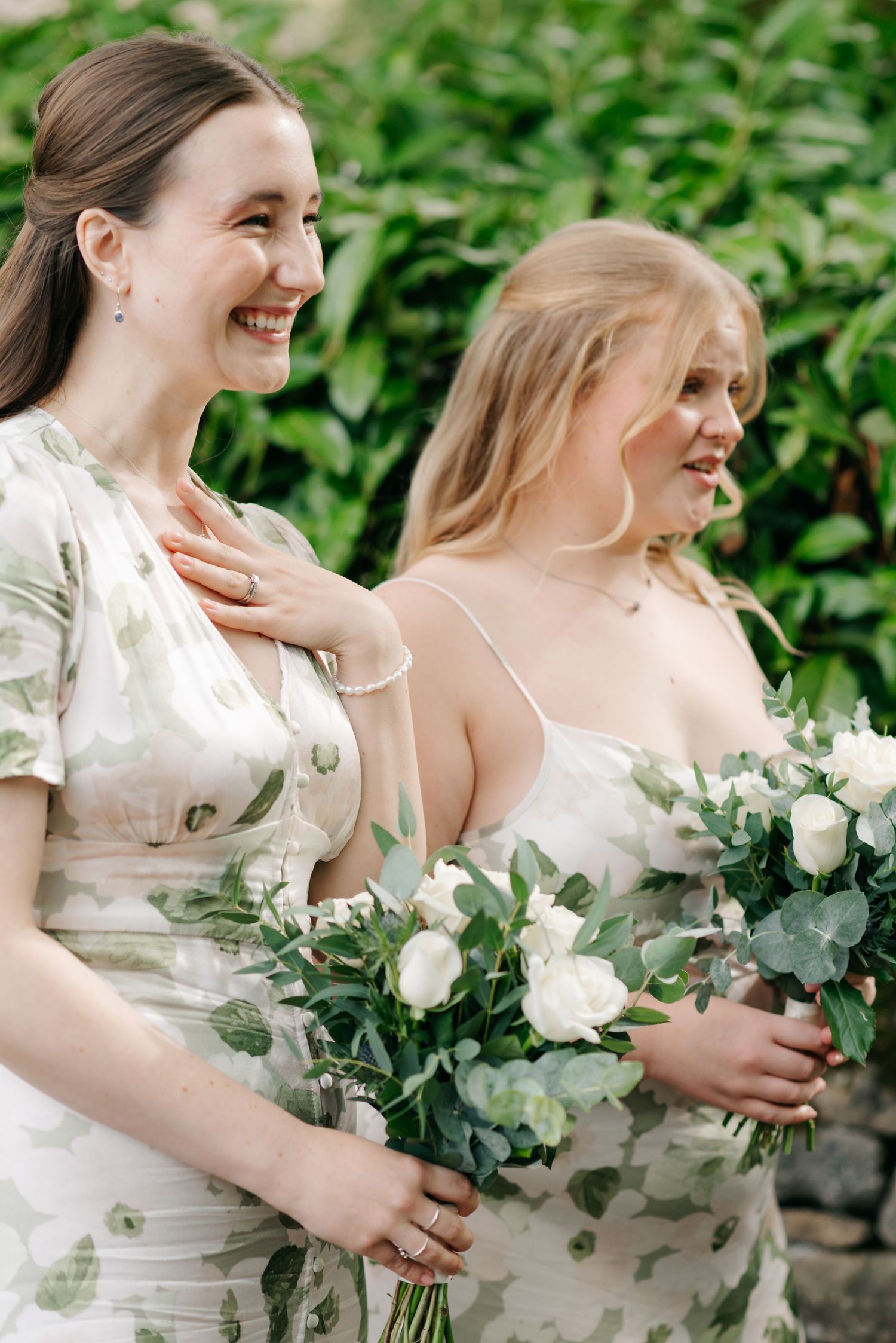 Bridesmaids in white dresses holding elegant bouquets of white roses and eucalyptus.