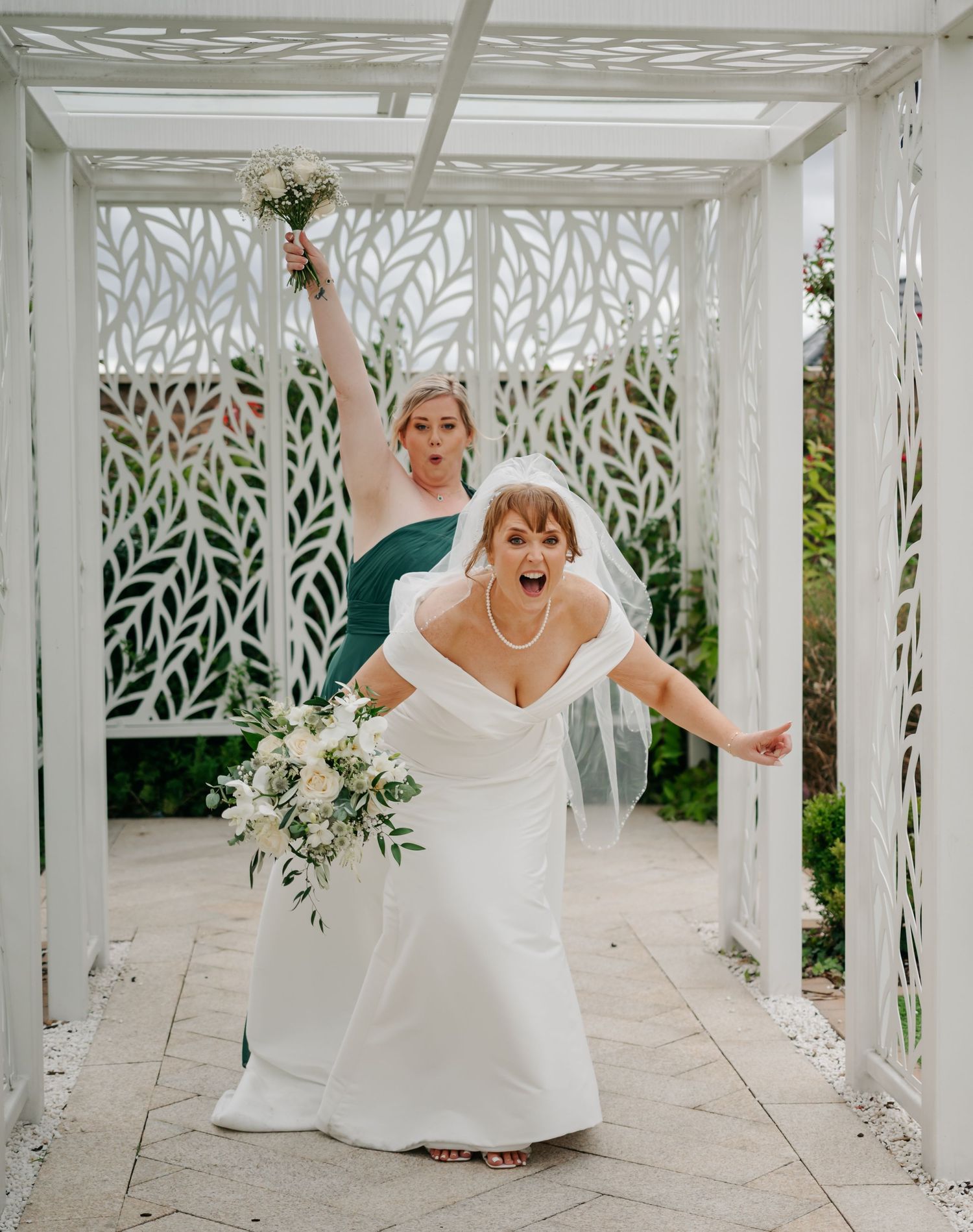 White pergola decorated with leaf cutouts creates elegant backdrop for celebratory wedding moments.