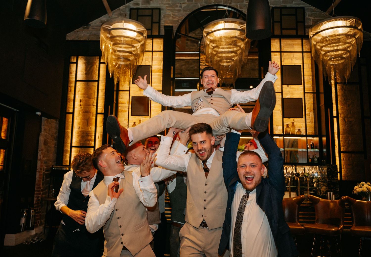 Wedding party celebrating with energetic dance moves at reception.