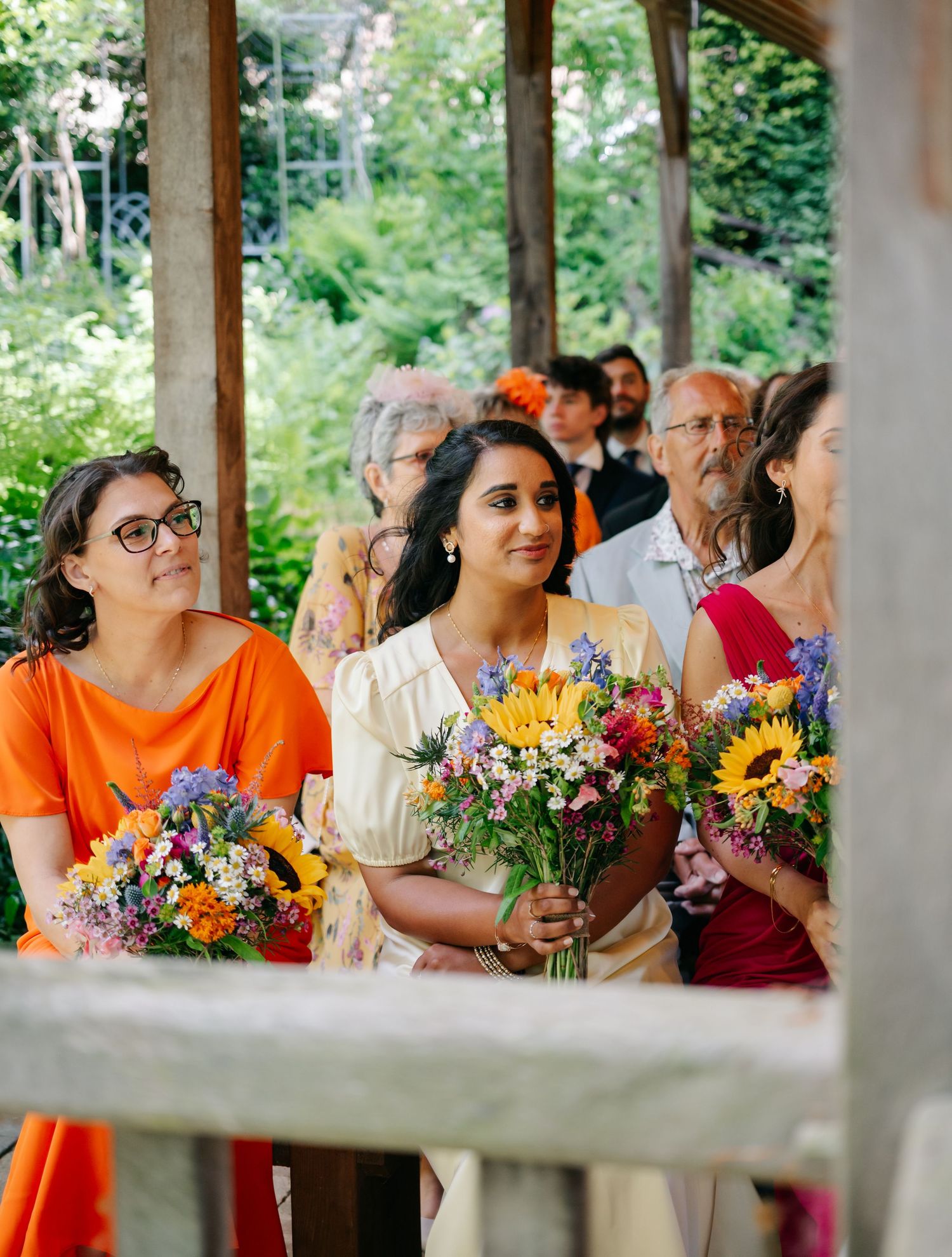 Wedding guests holding vibrant wildflower bouquets featuring sunflowers and colorful summer blooms.