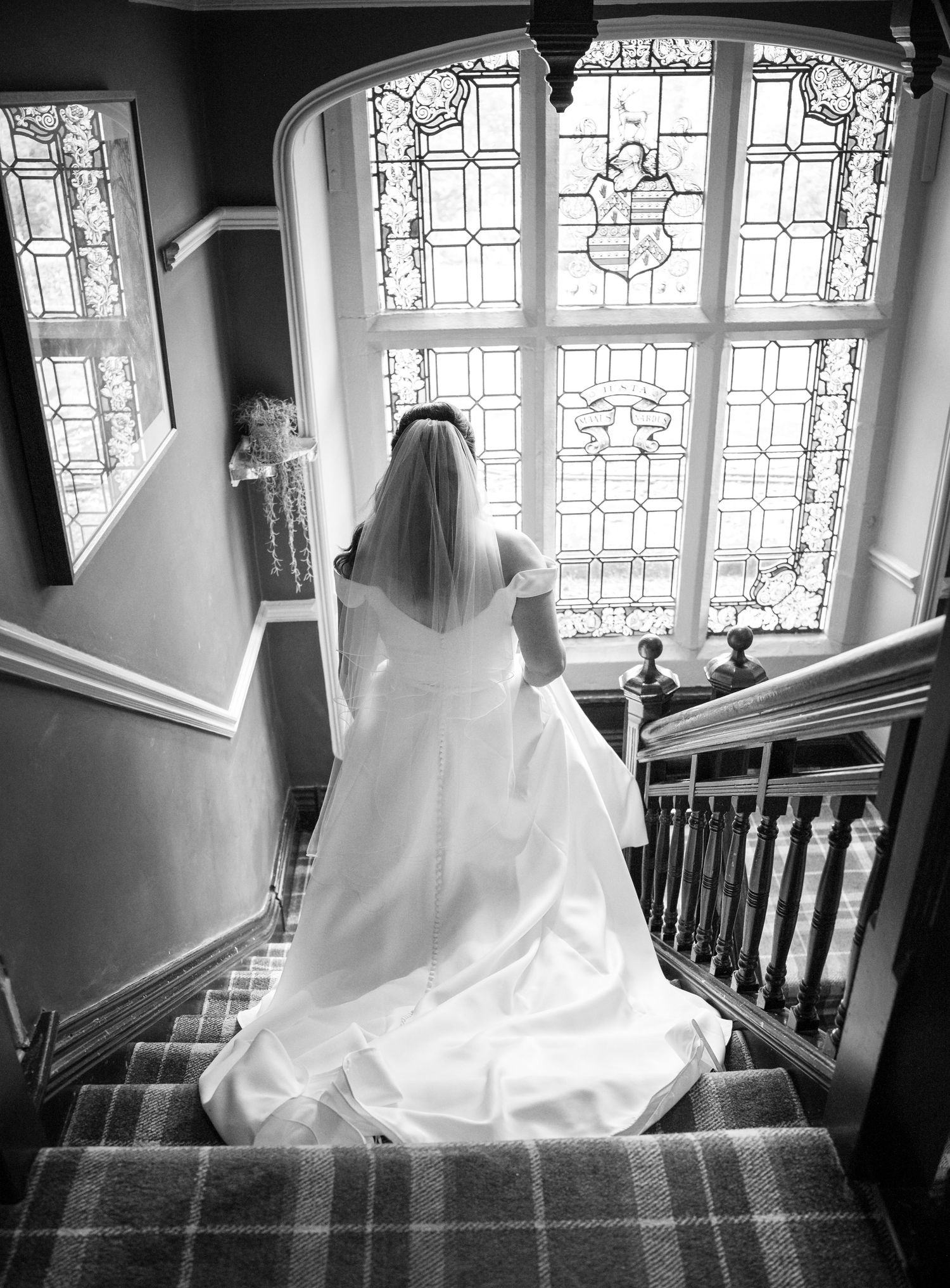 A series of black and white photos showing a bride in a flowing white dress descending an elegant staircase.