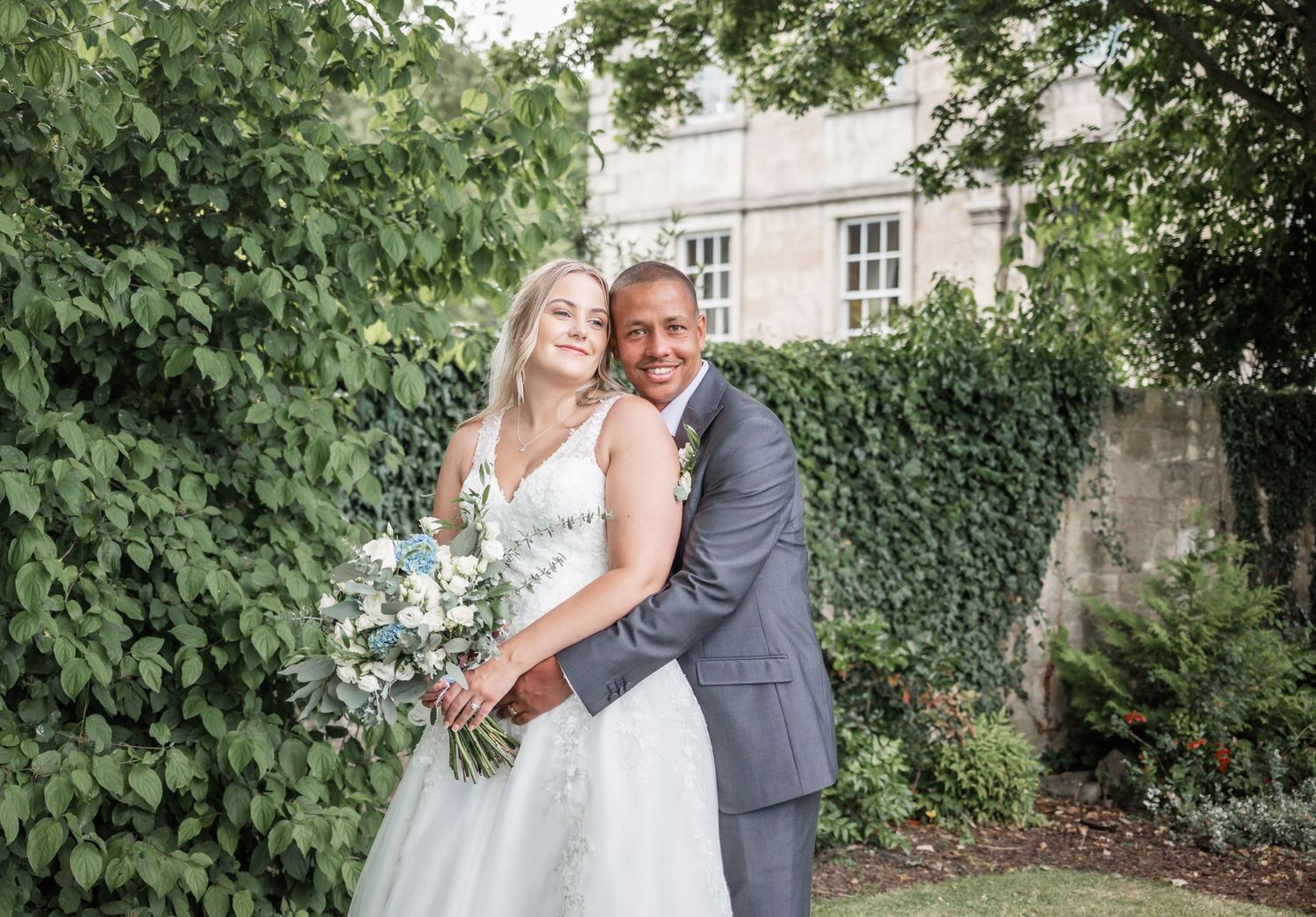 A romantic outdoor wedding portrait against ivy-covered stone walls.