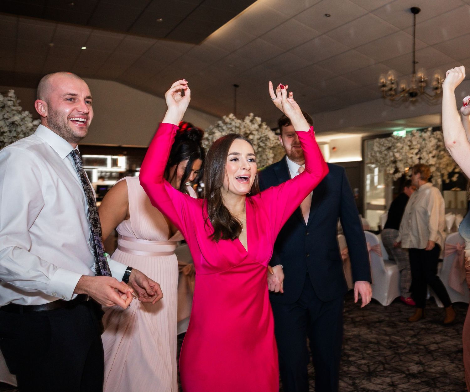 Wedding reception guests dancing and celebrating on the dance floor.