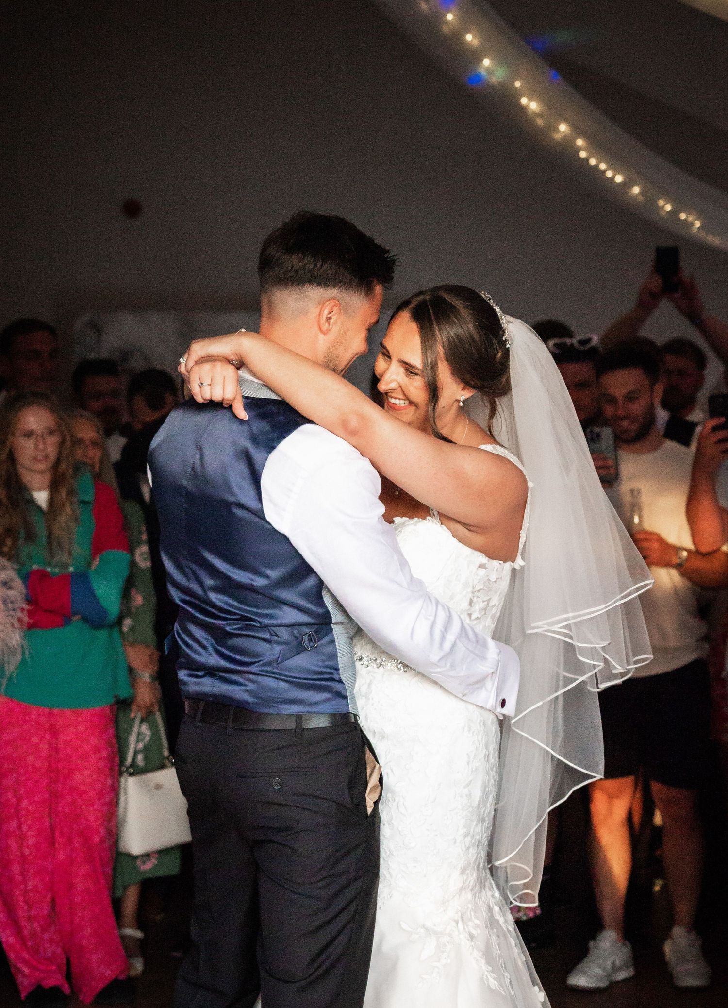 First dance between newlyweds under fairy lights at their wedding reception.
