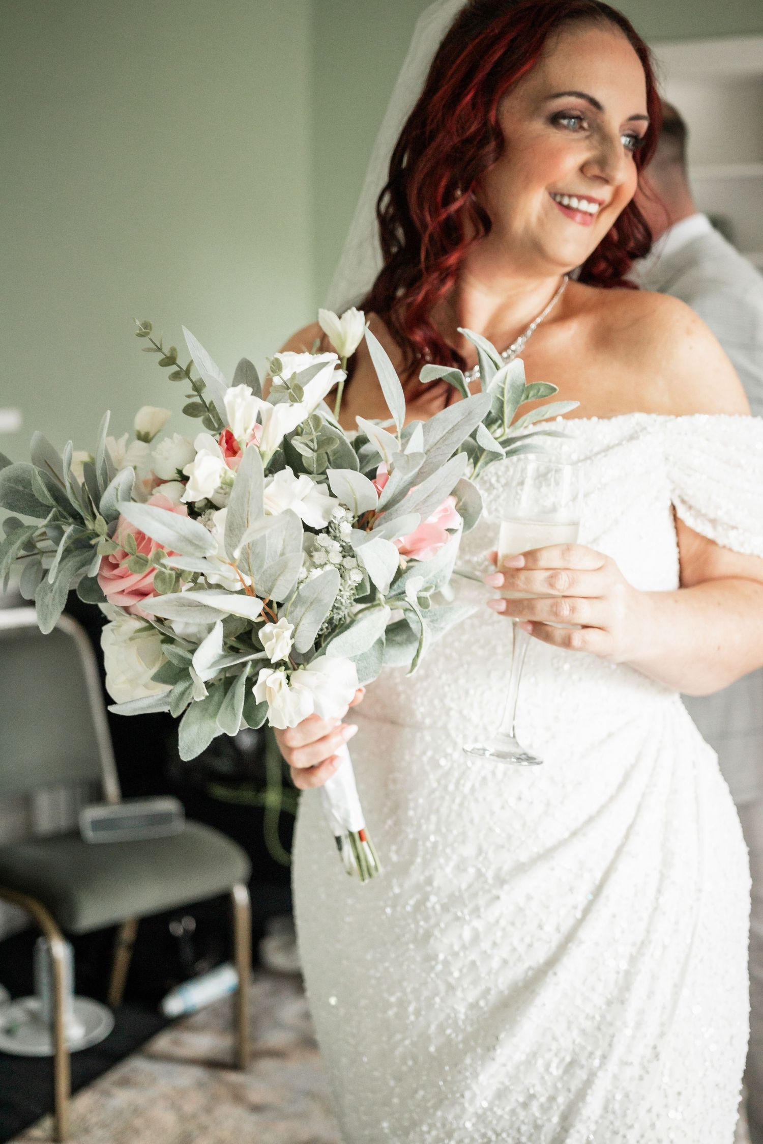 Bride with sequined dress holds elegant bouquet of white flowers and eucalyptus.