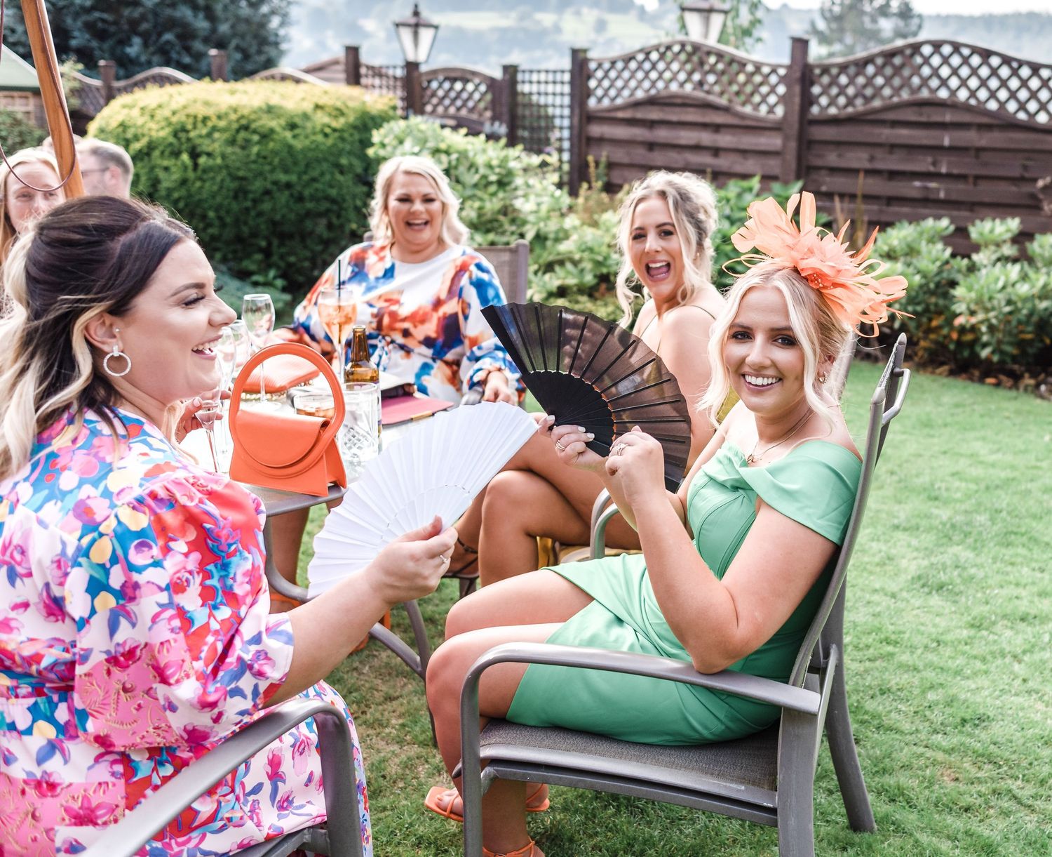 A group enjoying drinks and laughter in colorful attire at an outdoor garden party.