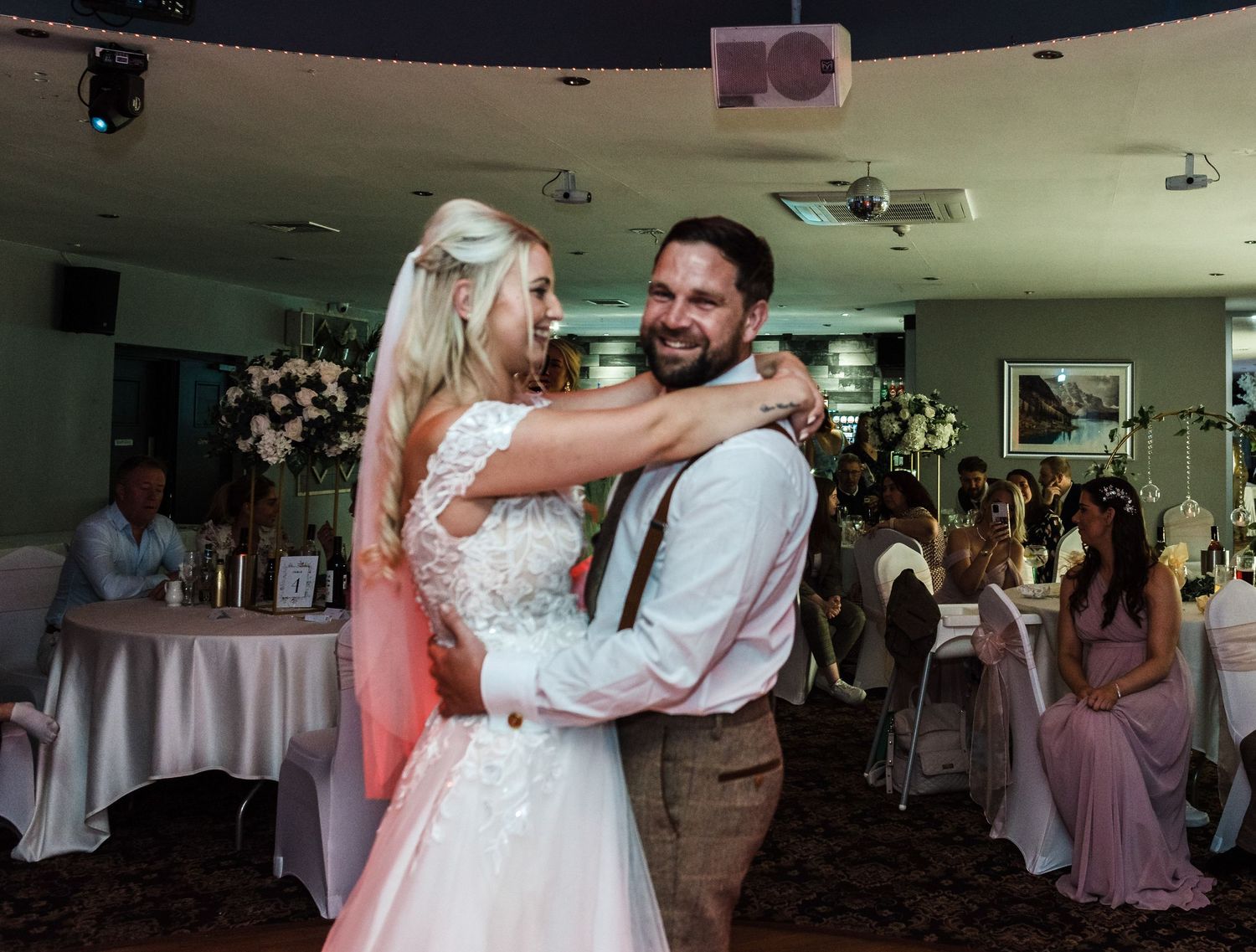A couple sharing their first dance in a beautifully decorated wedding reception venue.