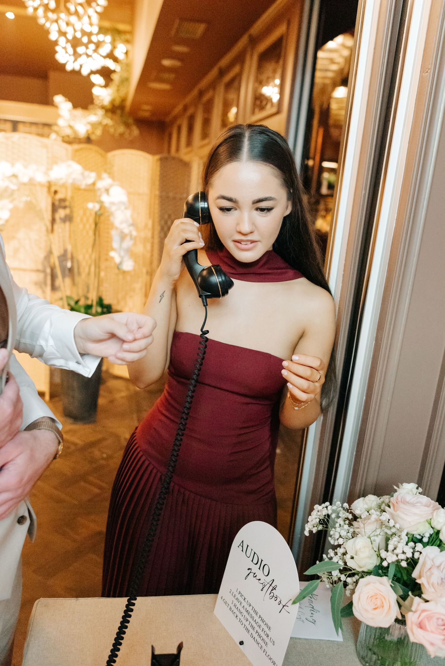 Wedding party member in burgundy dress holding a bouquet of pink and white flowers.