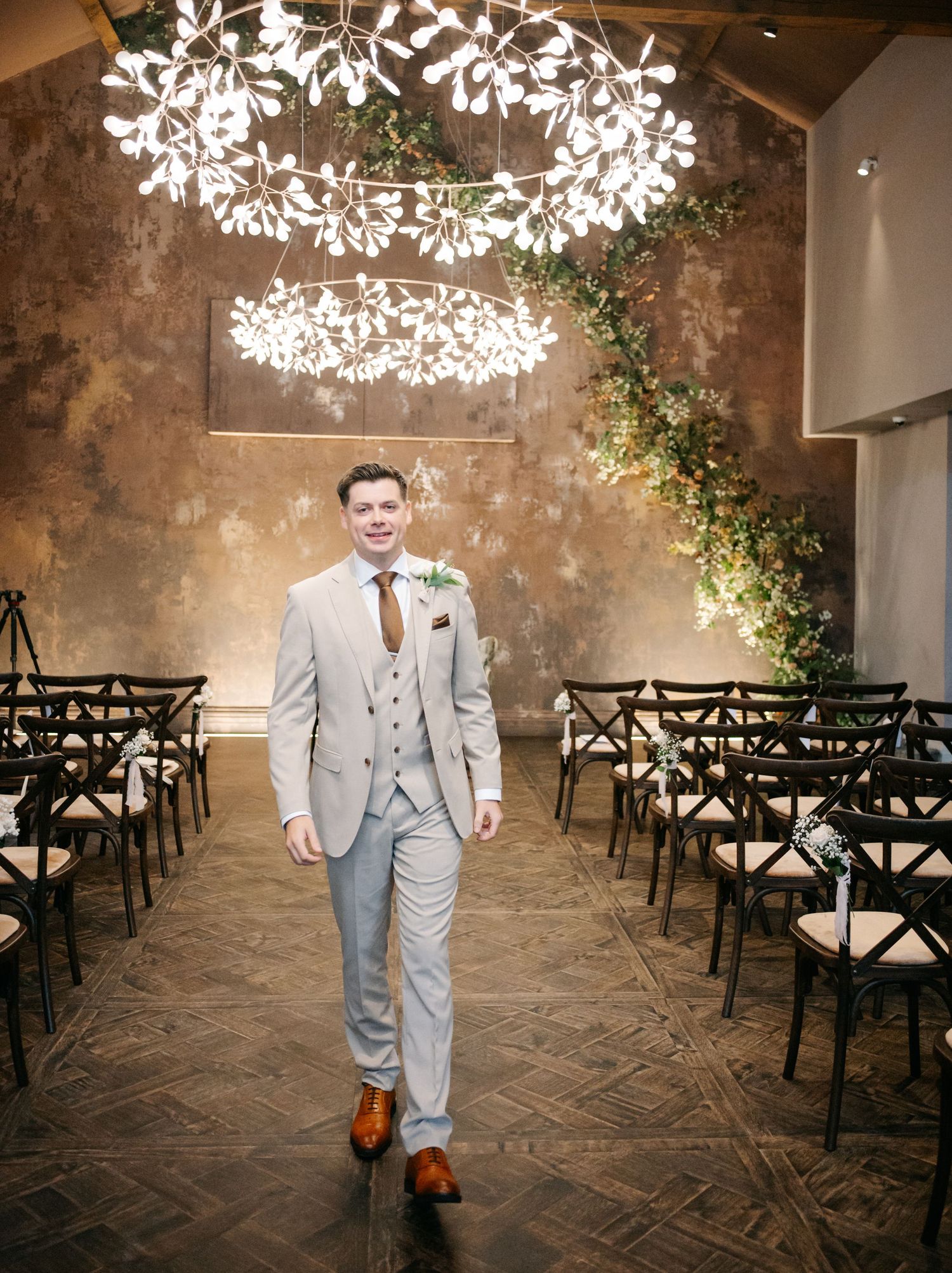 Elegant wedding venue with rustic brick walls, string lights, and dark wooden chairs.