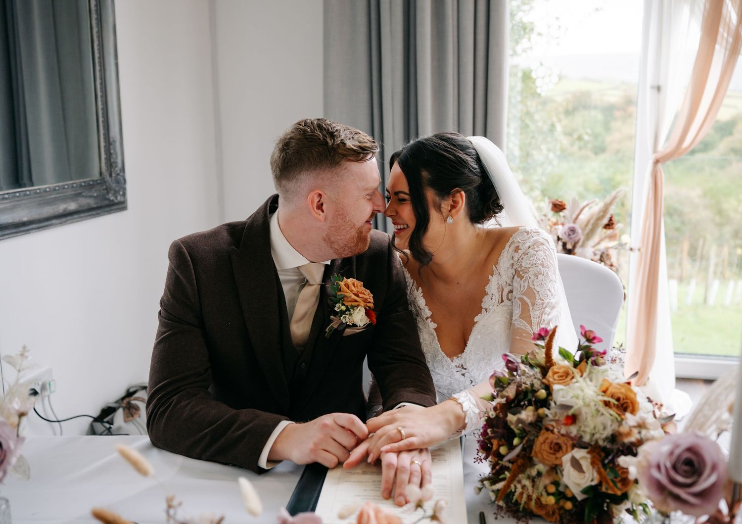 Newlyweds share an intimate moment at their reception table with a beautiful autumn floral centerpiece.