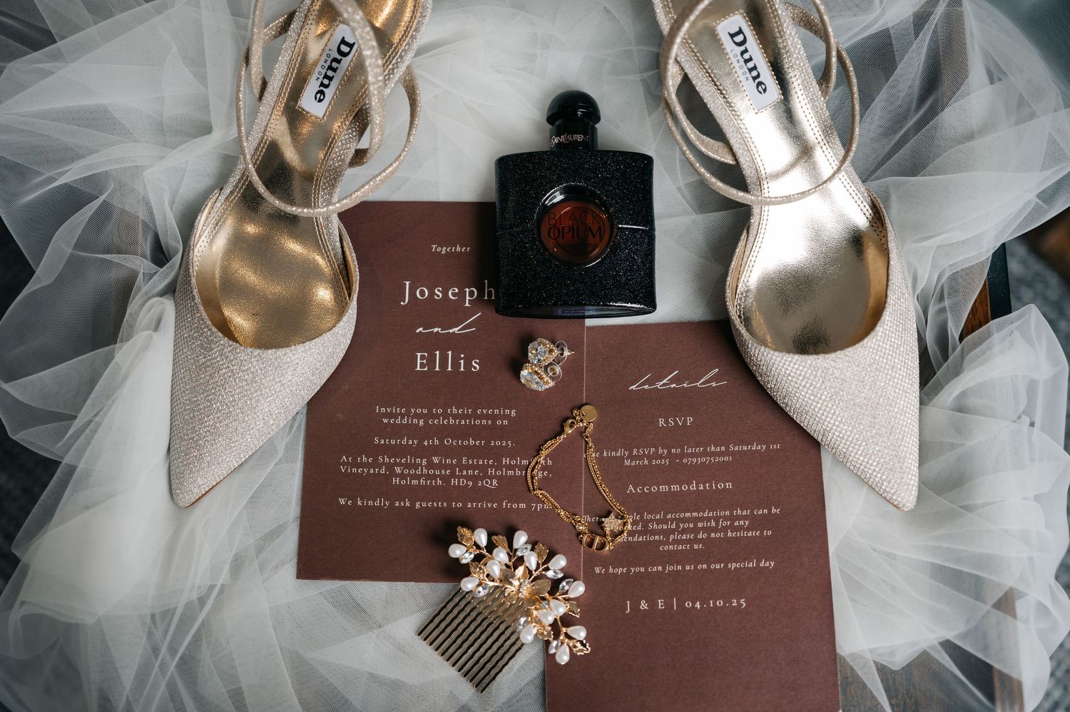 Wedding invitation suite in burgundy with delicate white tulle fabric and gold floral accents displayed elegantly.