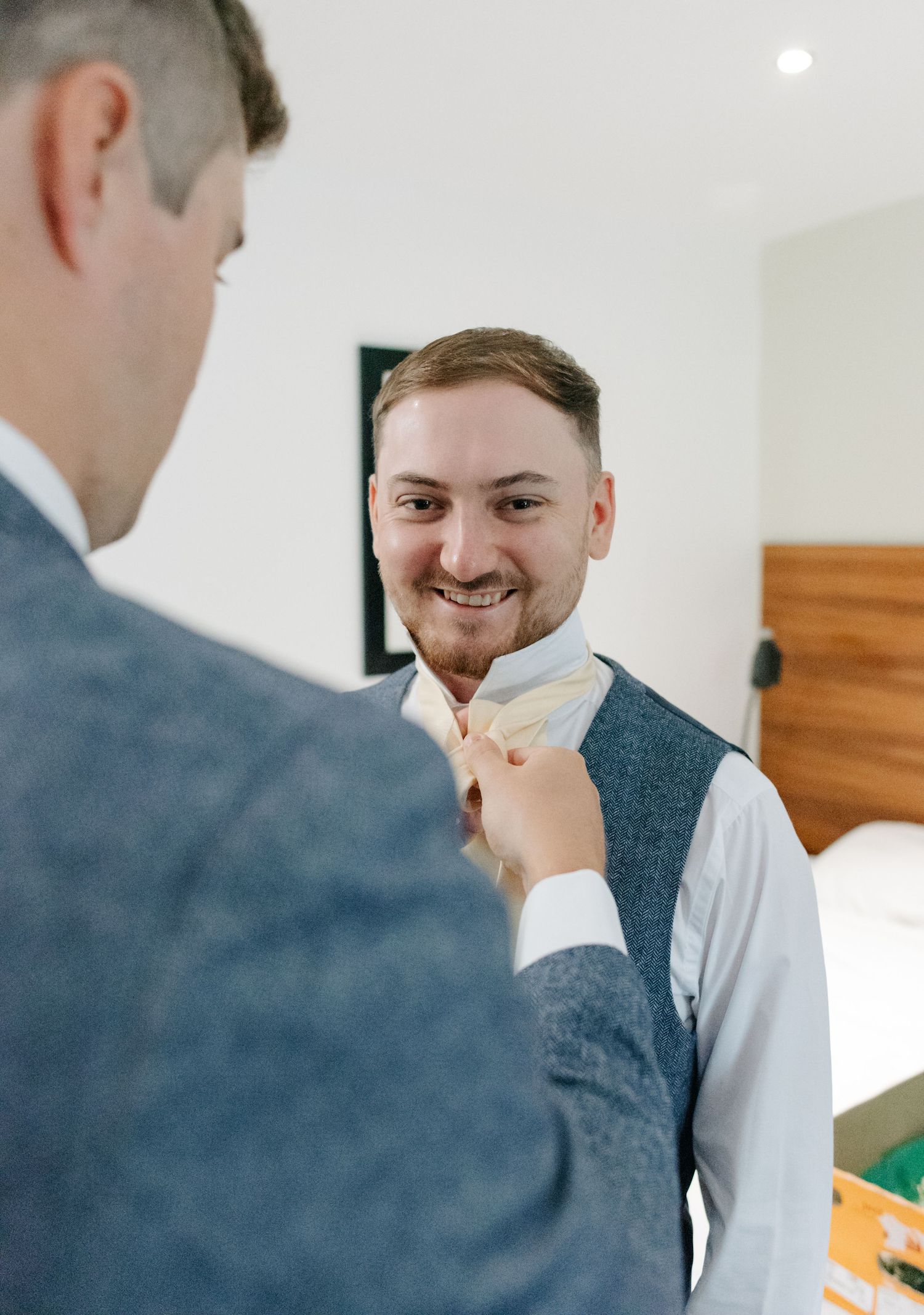 Groomsmen in grey suits sharing a lighthearted moment before the wedding ceremony.
