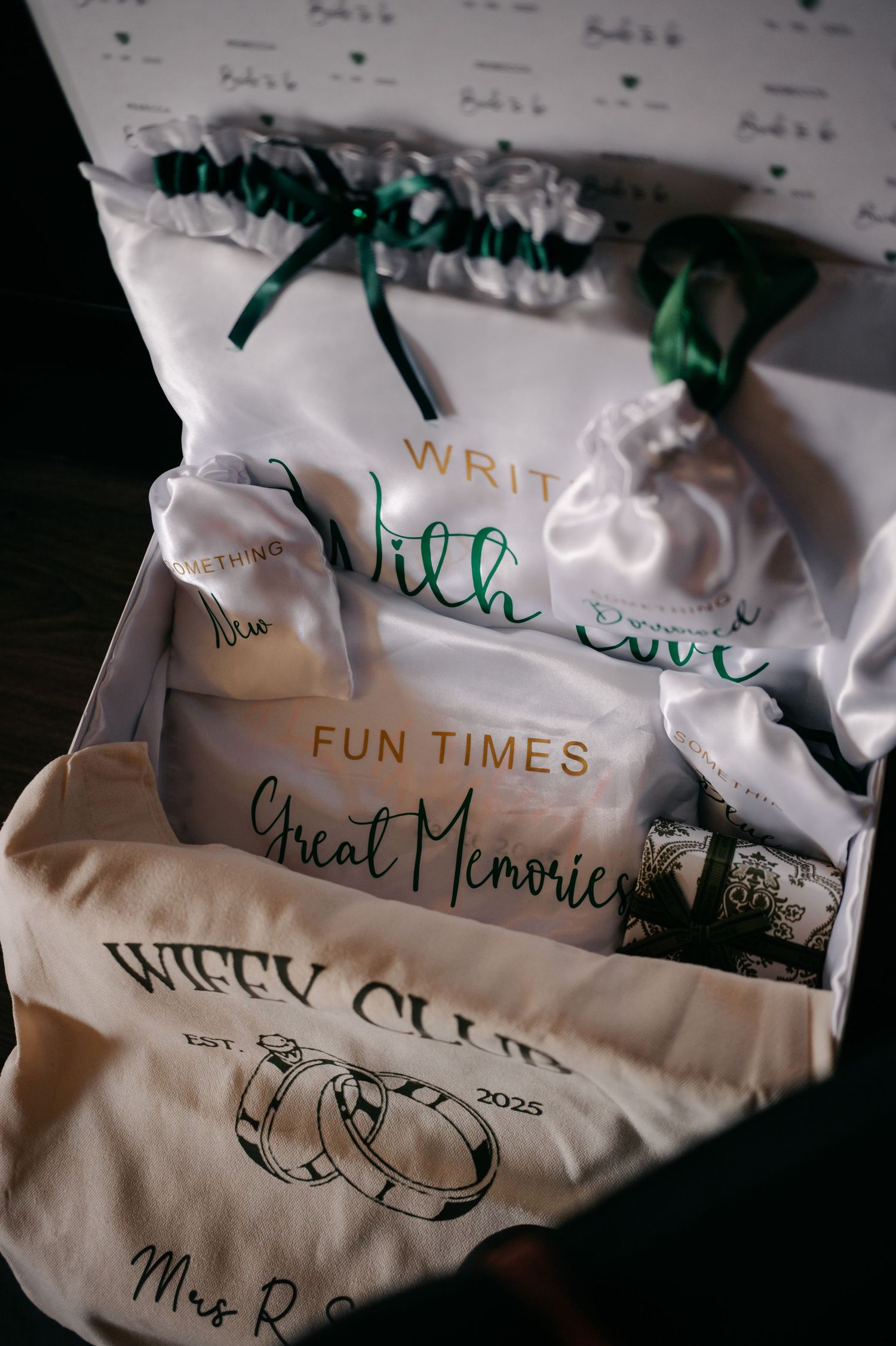 Wedding gift bags with handwritten text and green ribbons arranged in a row on white surface.