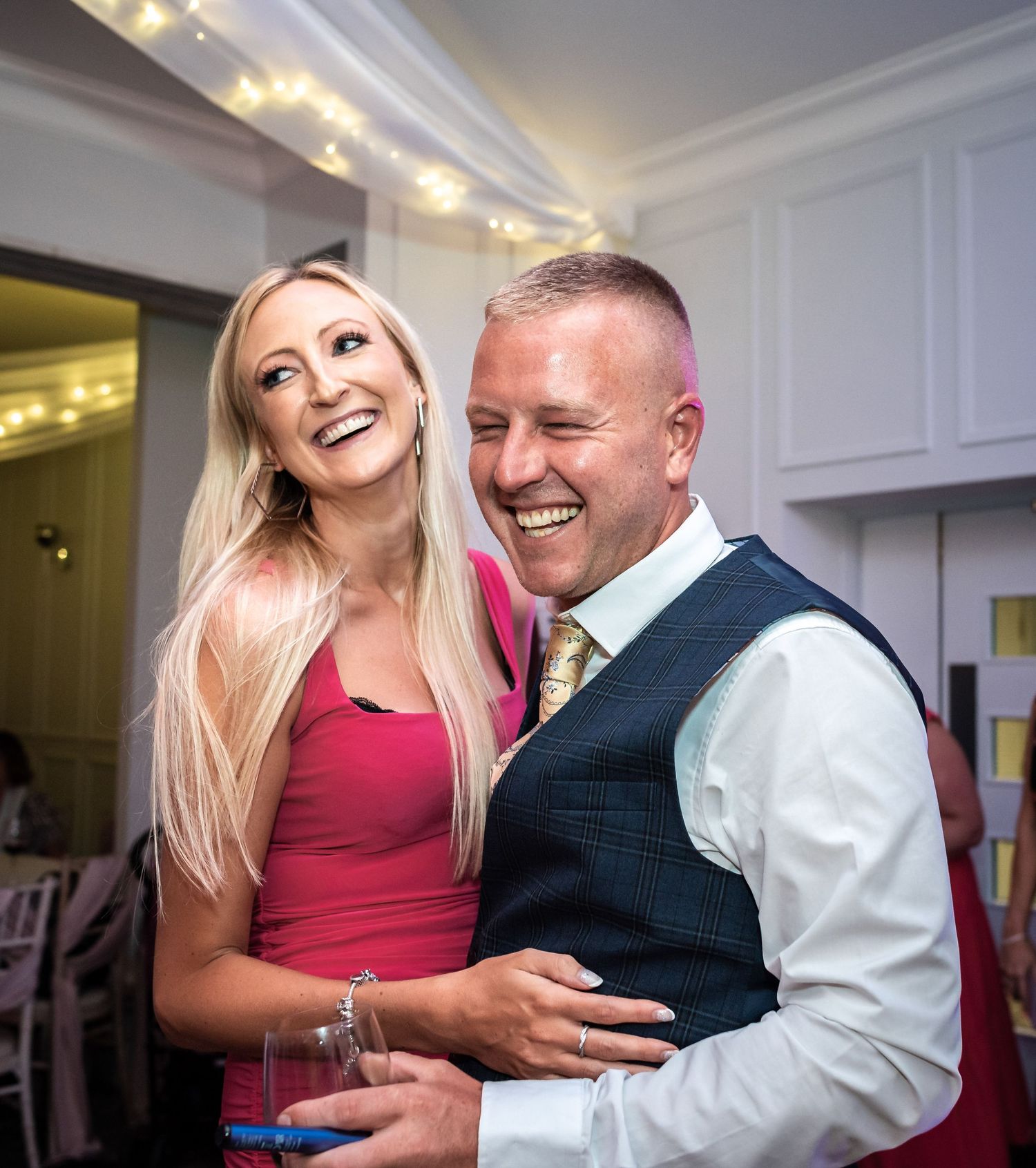 Candid celebratory moment during wedding reception with twinkle lights in background.