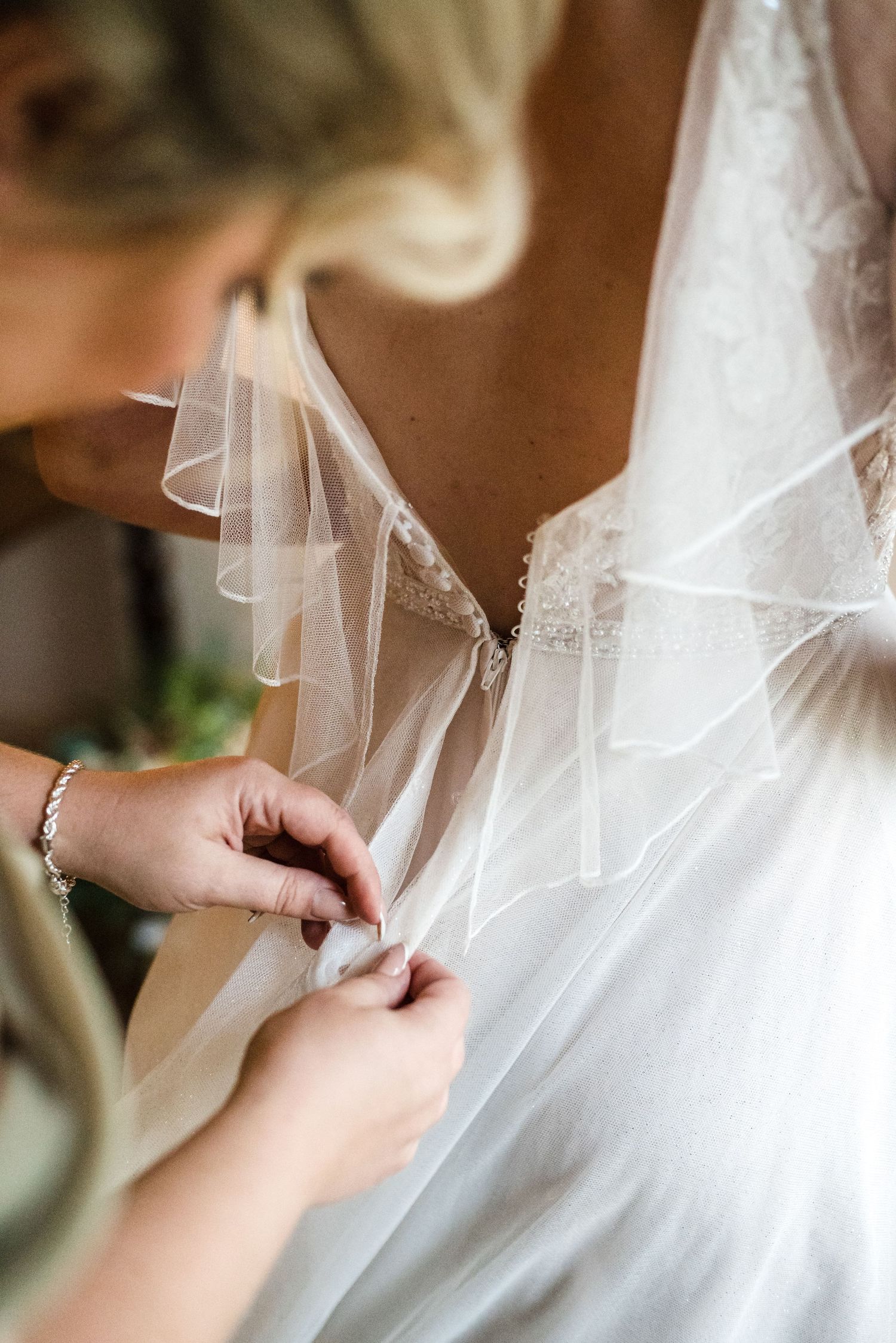 Close-up detail of hands adjusting a delicate white wedding veil.