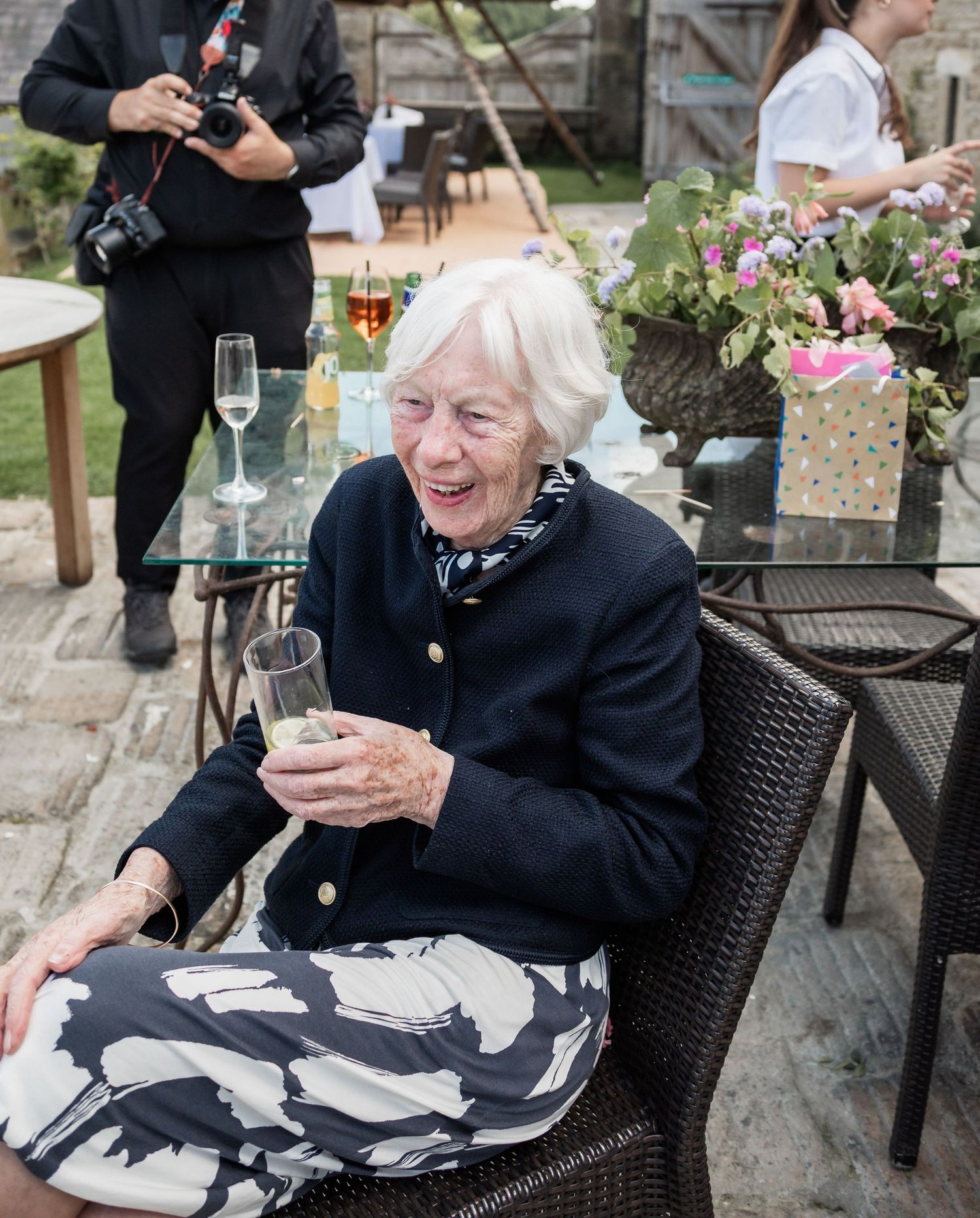Wedding guest enjoying champagne at outdoor reception with floral decorations.