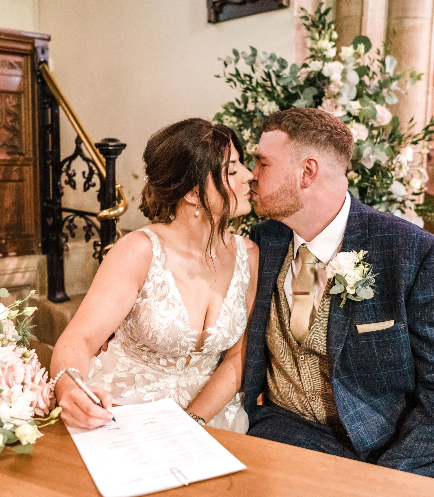 Intimate moment captured during document signing at church wedding ceremony.