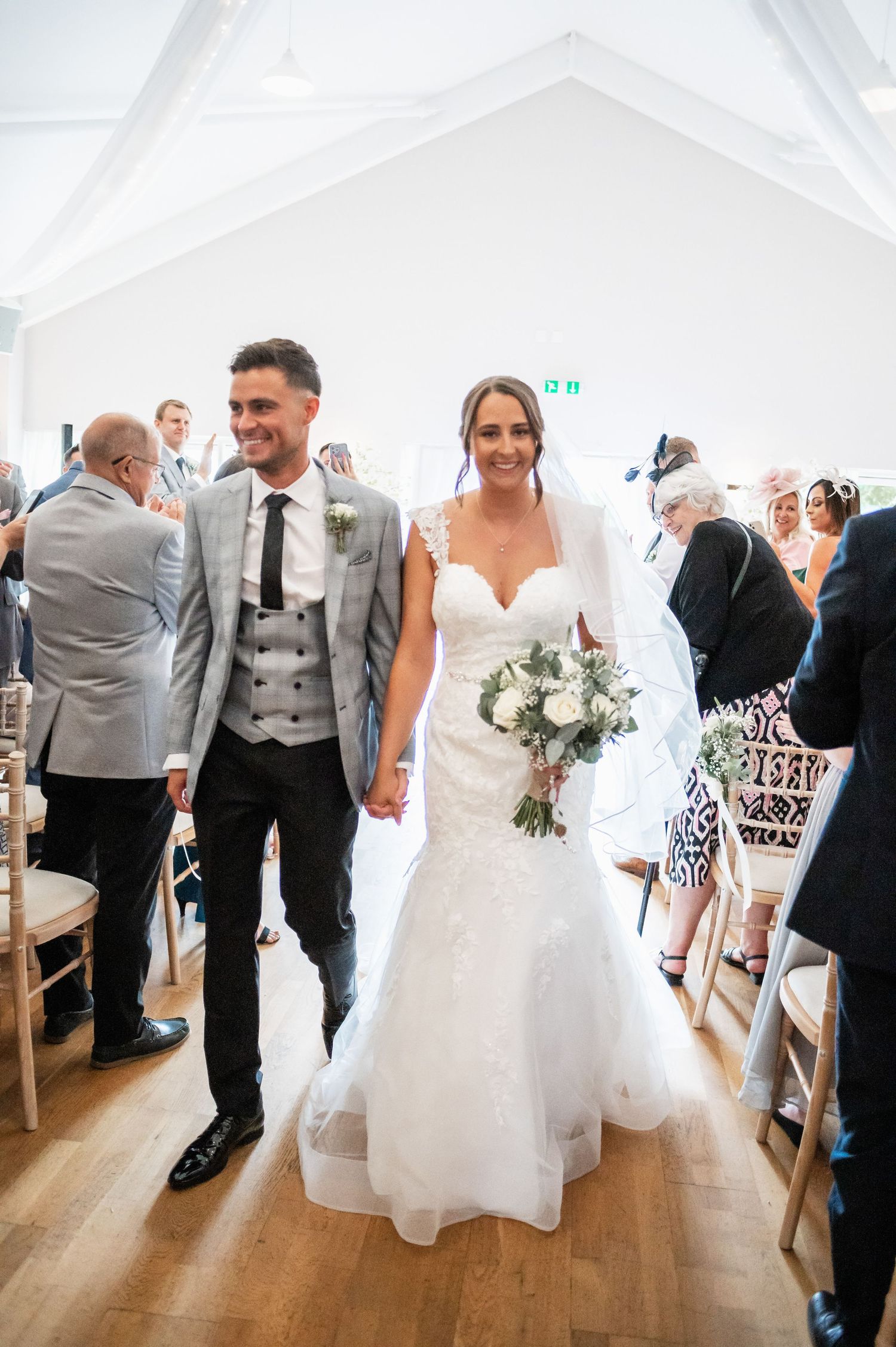 A couple walking down the aisle while guests look on in a bright, modern venue.